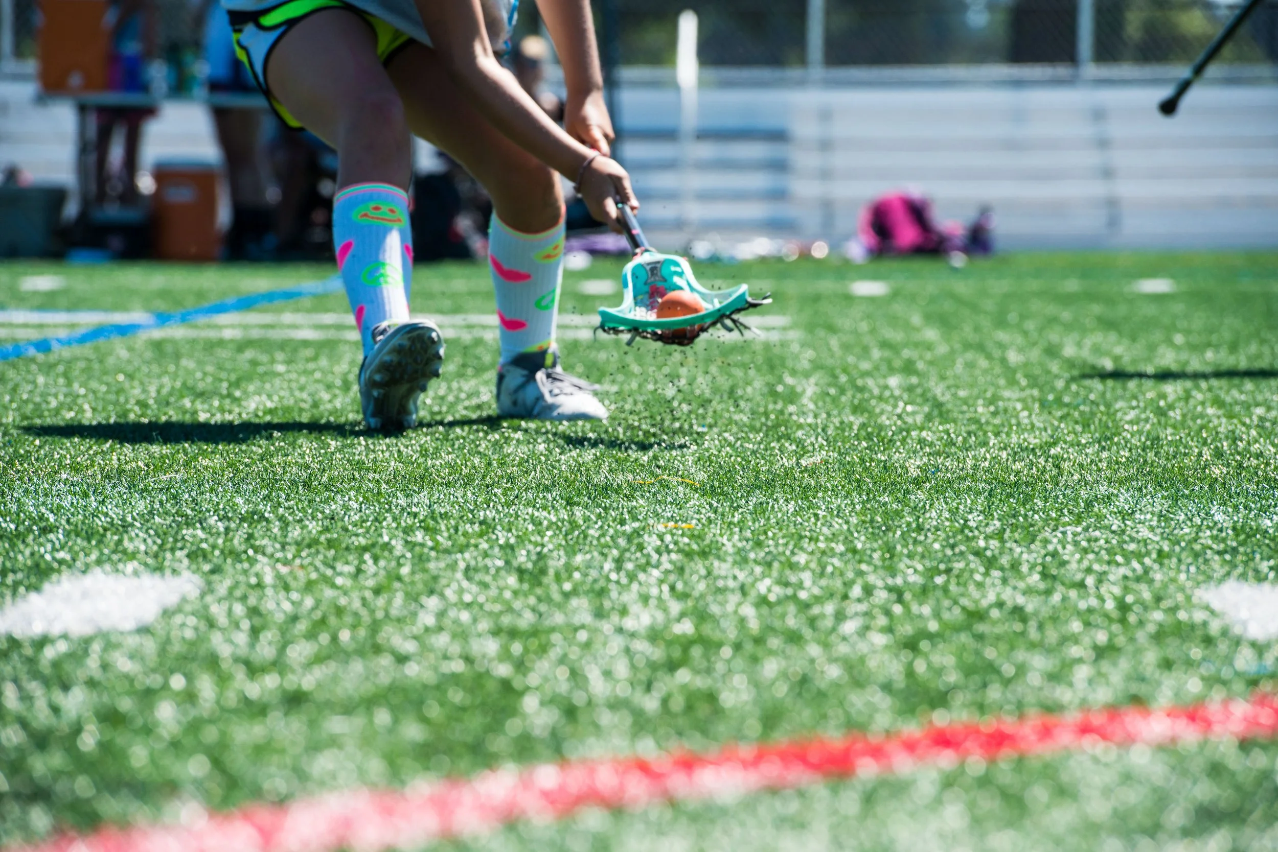 lacrosse player picking up ground ball while wear fun, bright socks
