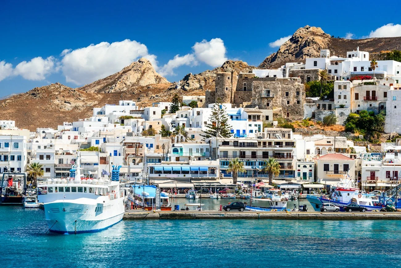 Naxos harbor with whitewashed hillside buildings and boats along the waterfront