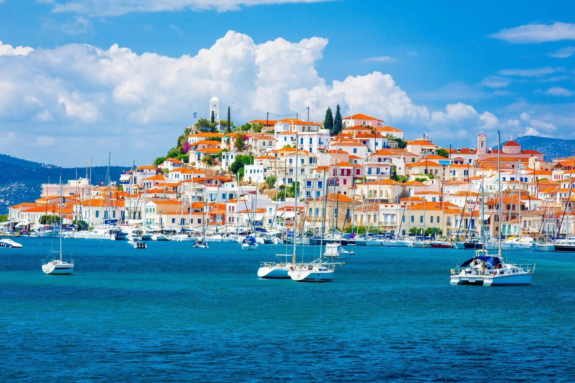 Poros harbor with white buildings, sailboats, and blue Aegean water