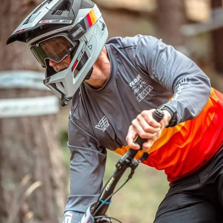 A mountain biker wearing a helmet and goggles riding a bike on a trail in a custom designed Freerider jersey