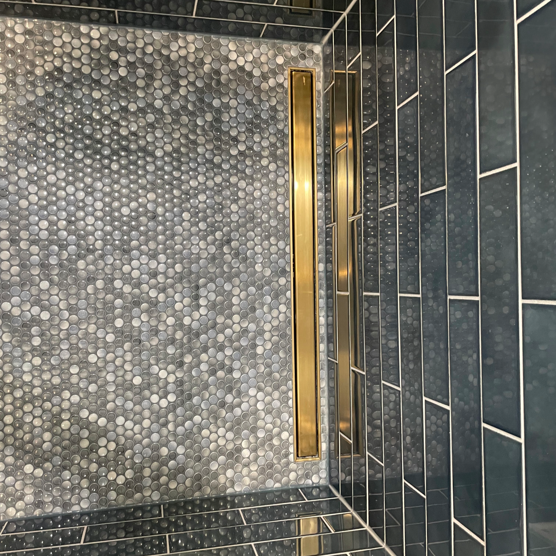 Penny tile shower floor with a coordinating brushed gold linear drain.
