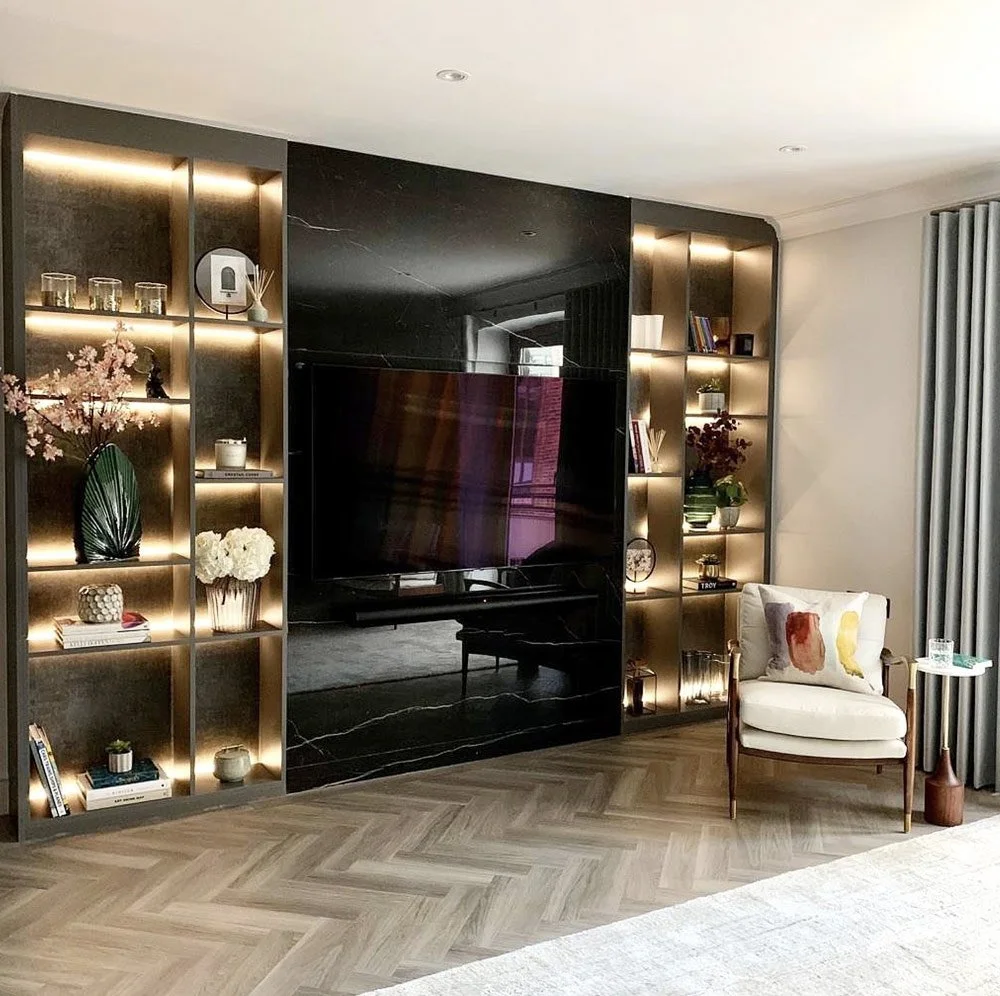 Custom media wall with integrated display shelving, concealed storage and ambient LED lighting designed for a modern living room.