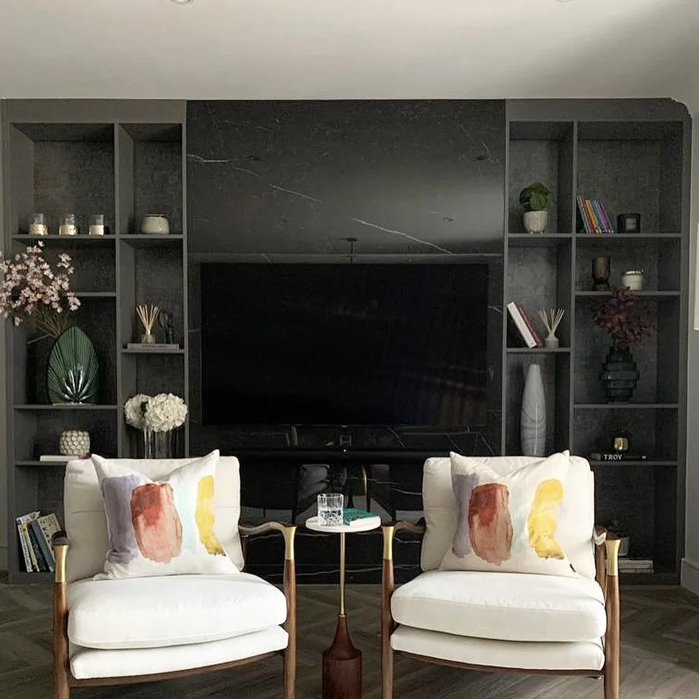 Luxury fitted media wall featuring black marble-effect panels, warm LED display shelving and integrated television surround.