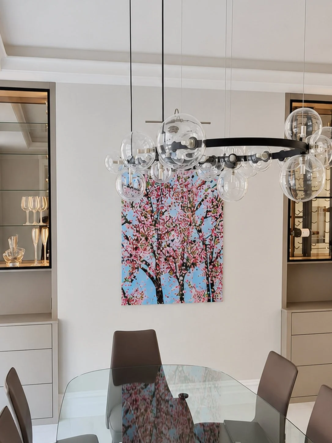 Bespoke display and wine cabinets in a soft cashmere finish featuring illuminated glass shelving, integrated storage and black aluminium framed doors.