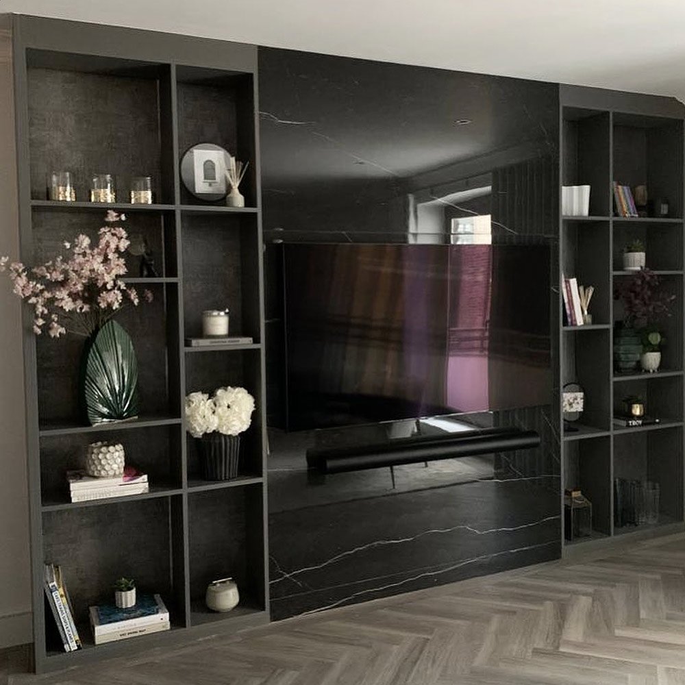 Bespoke black wenge TV wall with integrated fireplace, illuminated shelving and fitted living room storage in a luxury London home.