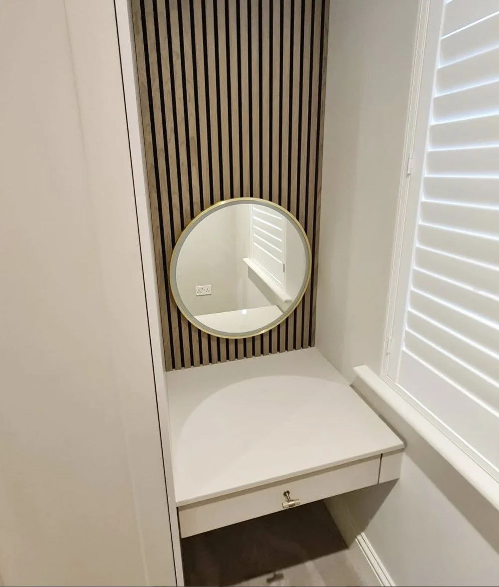 A bespoke bedroom vanity area featuring decorative slatted wall panelling, integrated seating and contemporary styling.