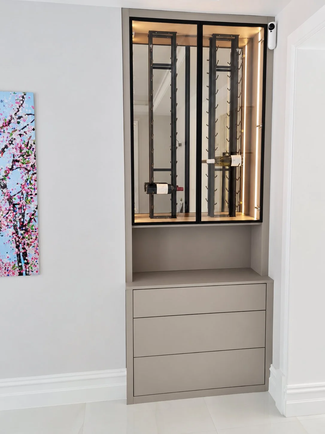 A luxury wine and display cabinet featuring integrated bottle storage, illuminated shelving and made-to-measure cabinetry.