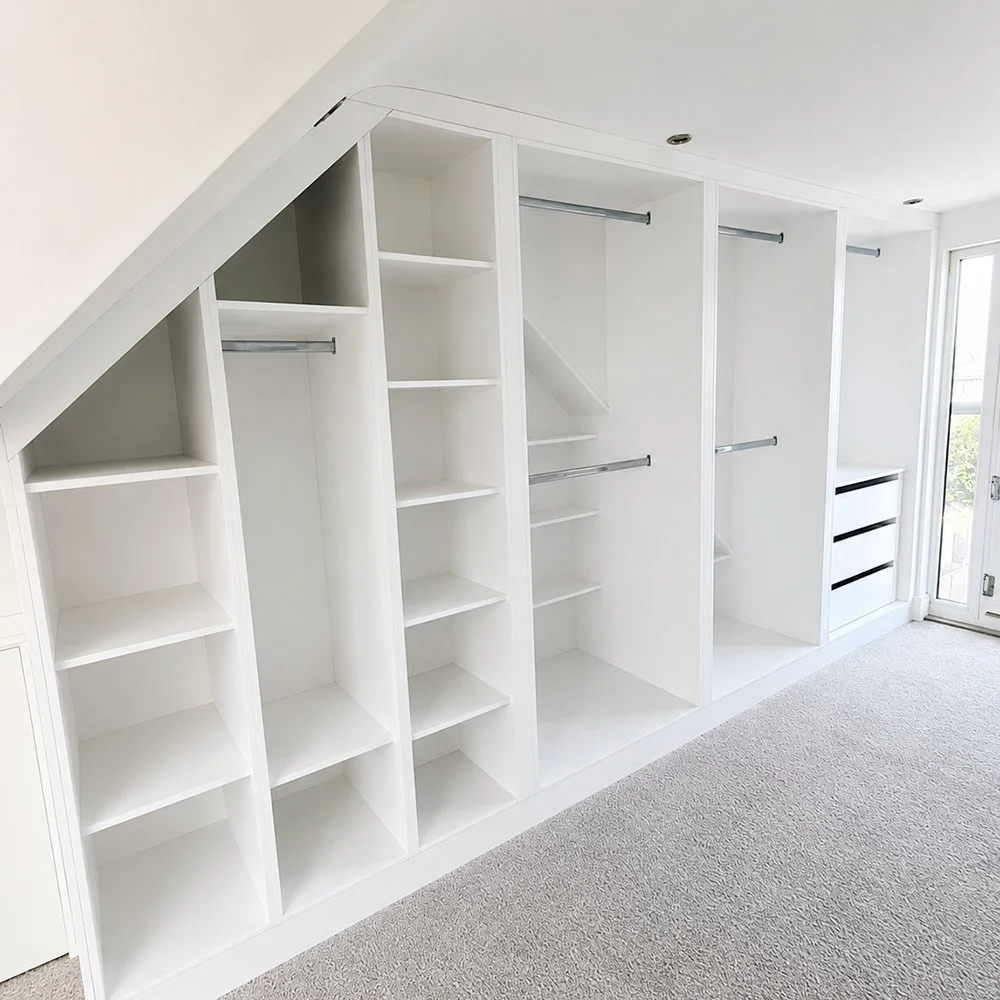 A bespoke loft storage solution featuring full-height fitted wardrobes tailored precisely to the shape of the room.
