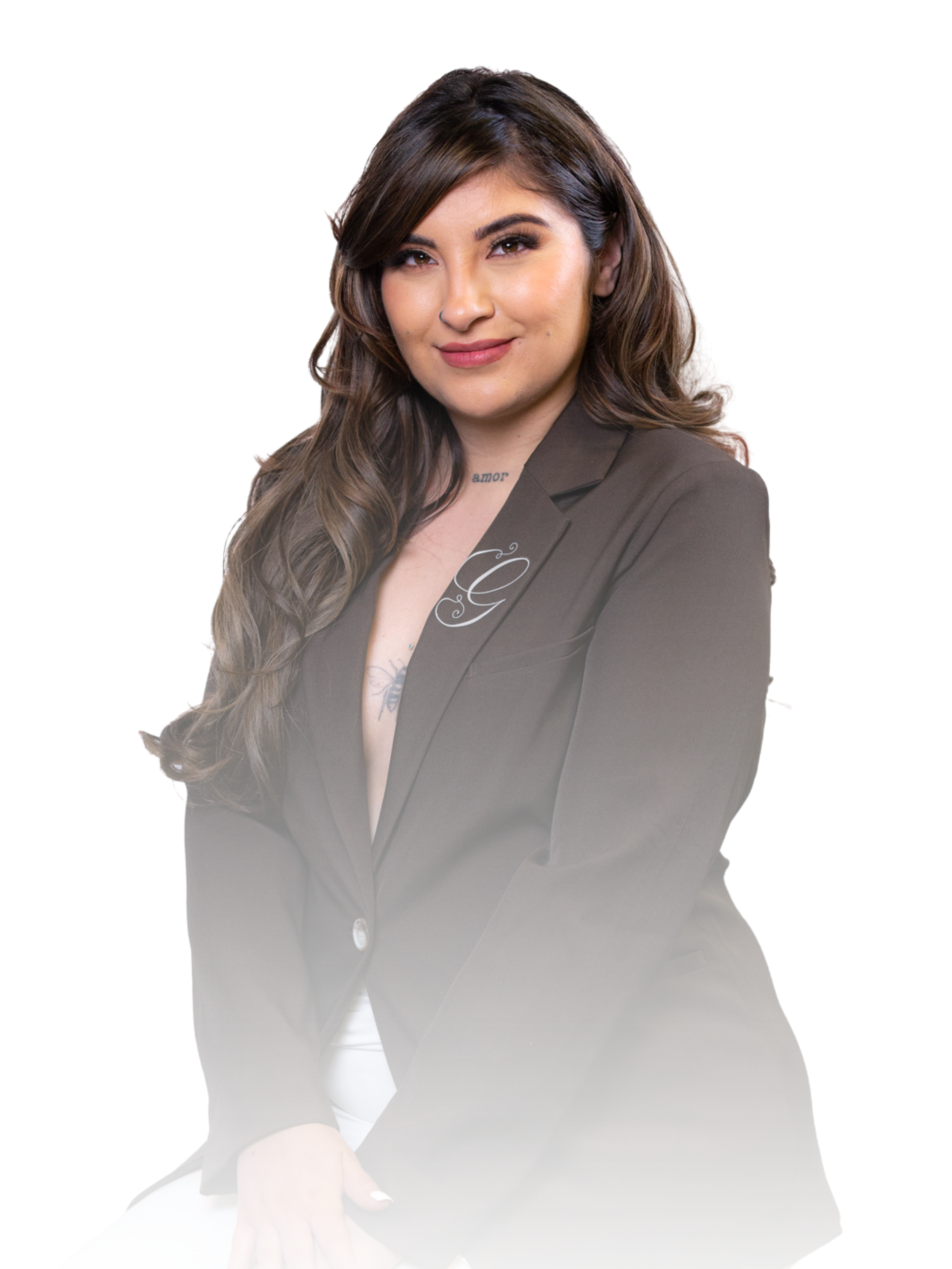 A woman with long wavy brown hair, wearing a dark blazer, looking at the camera with a slight smile