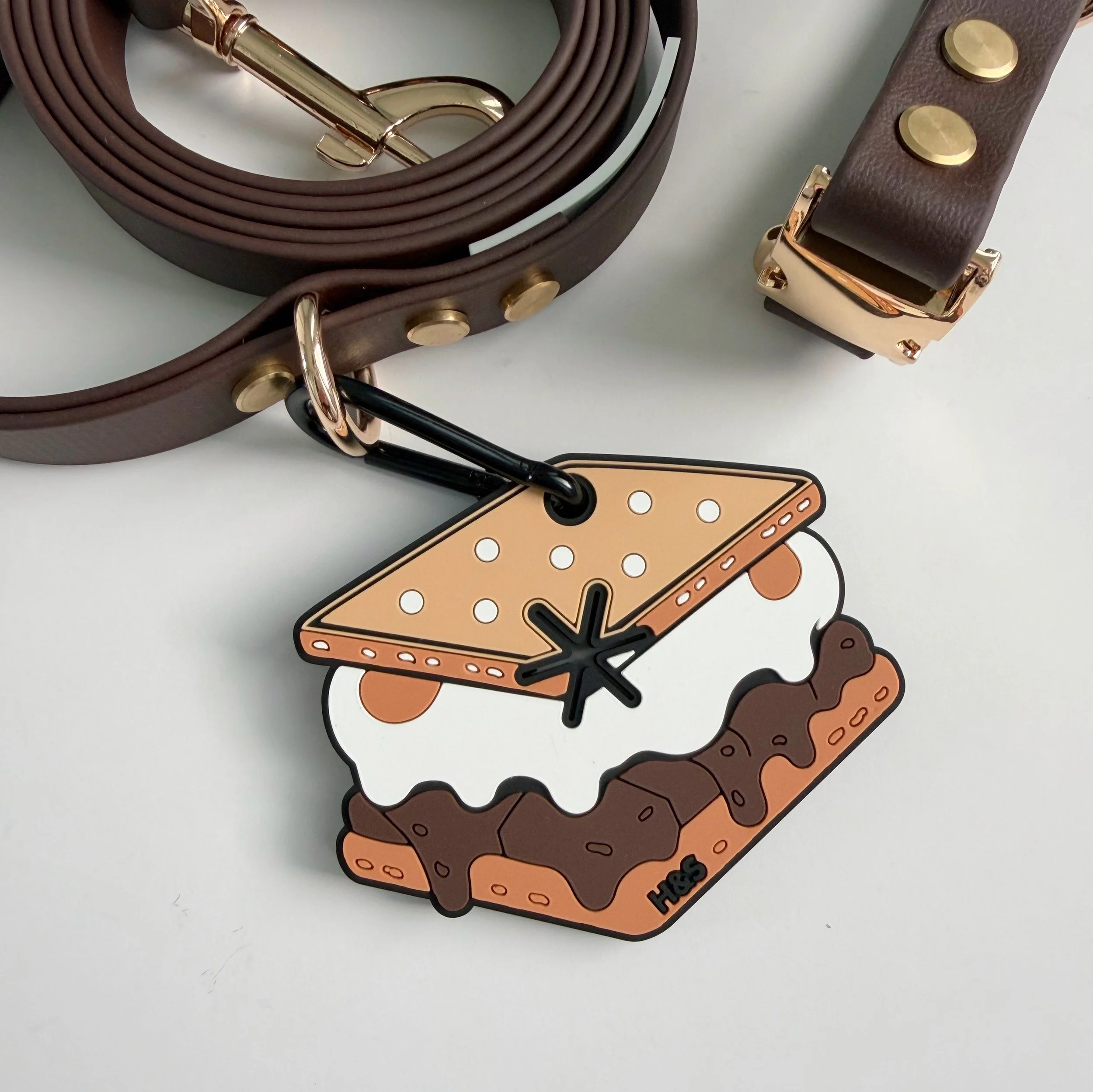 S'more Shore Loop hands free dog waste bag carrier shaped like a s'more, clipped to a brown BioThane leash with gold hardware from Hund and Shore