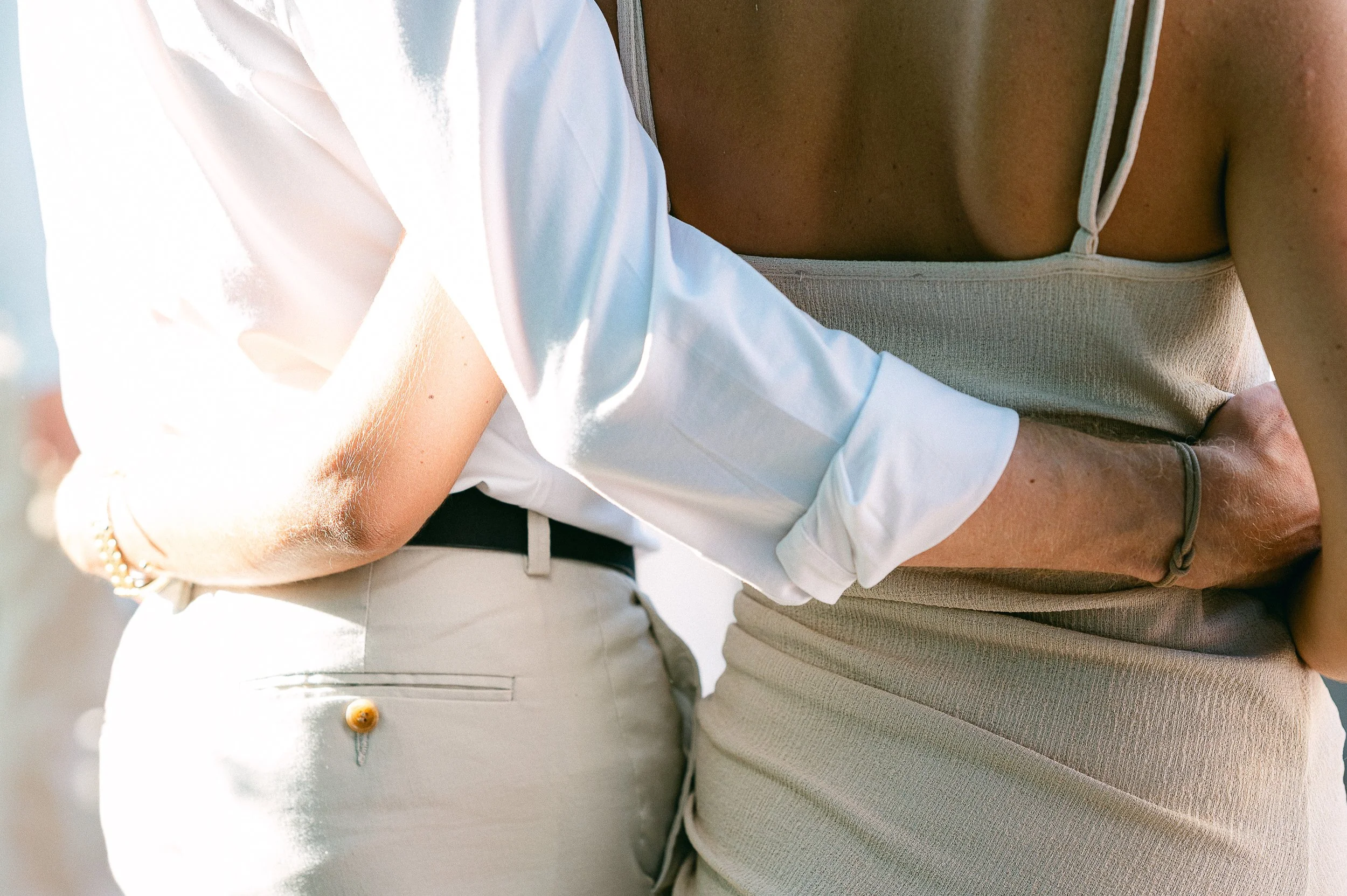 Deux personnes portant des vêtements décontractés, dont un en beige et l'autre en blanc, sont proches l'une de l'autre dans une position intime.