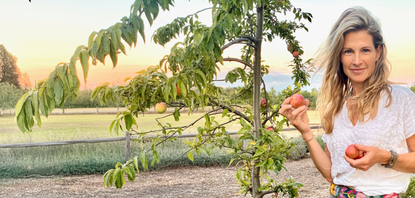Jen Boulden at Anavo Farm, holding peaches from the orchard at golden hour.
