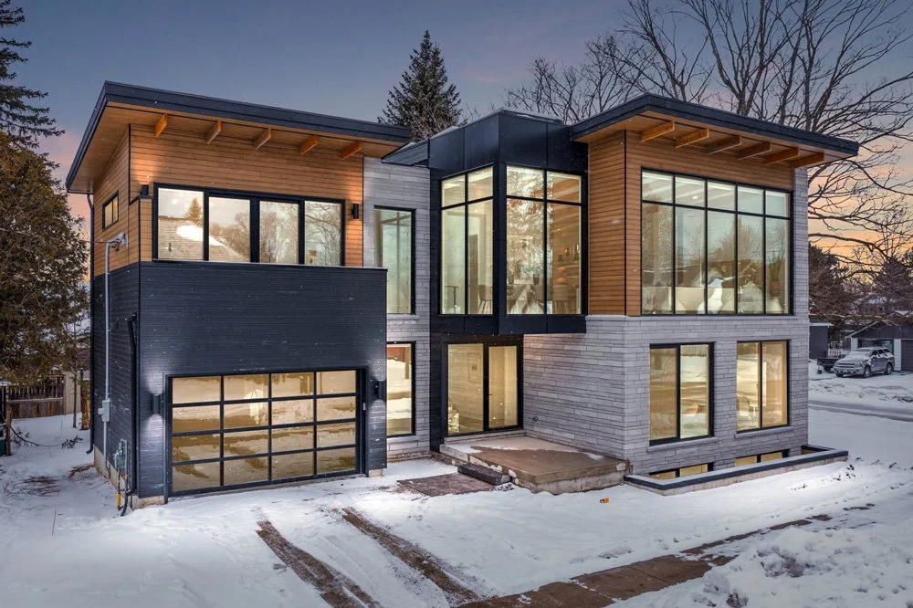 Alice house architecture project in Thornbury Ontario | Front of house at night with house lights on and snow on ground