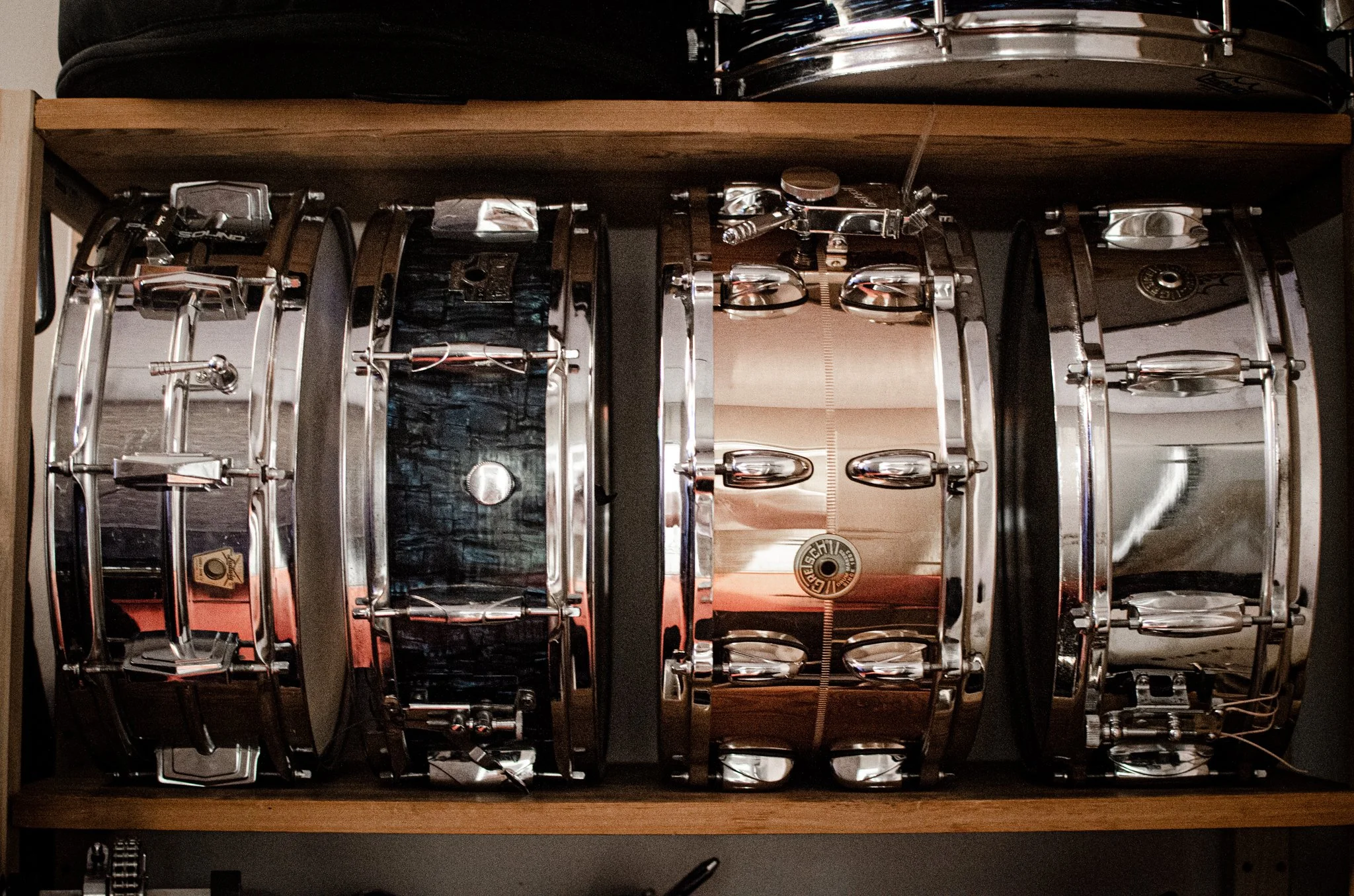 Fire metall trommer med skarpe kanter, stablet på en trehylle.