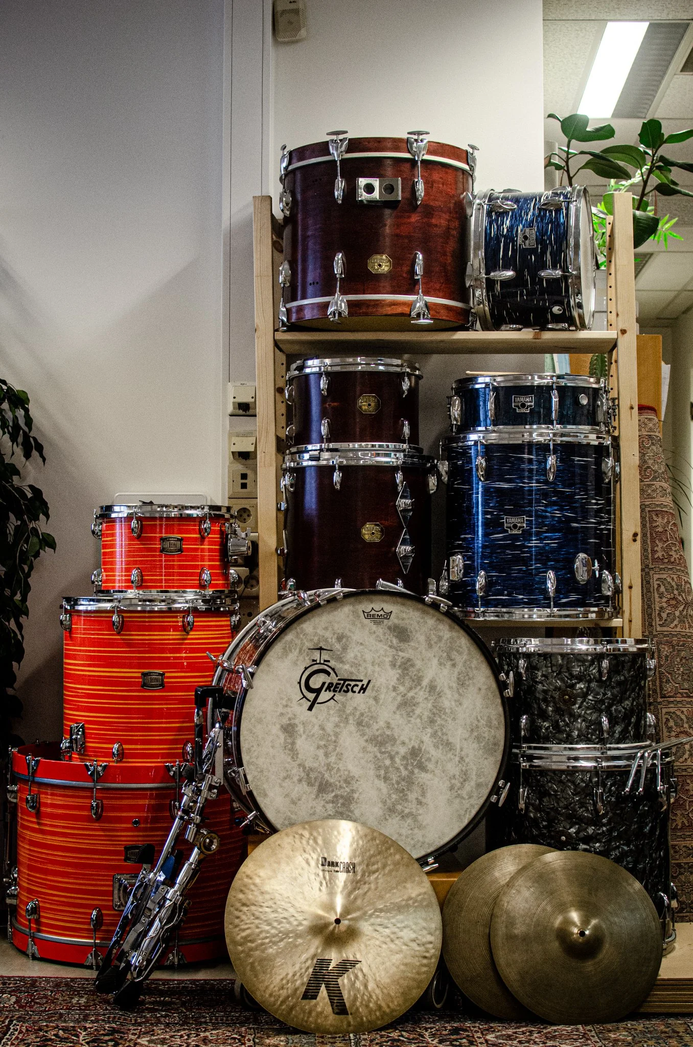 En samling av forskjellige trommer og trommesett plassert på et teppe.