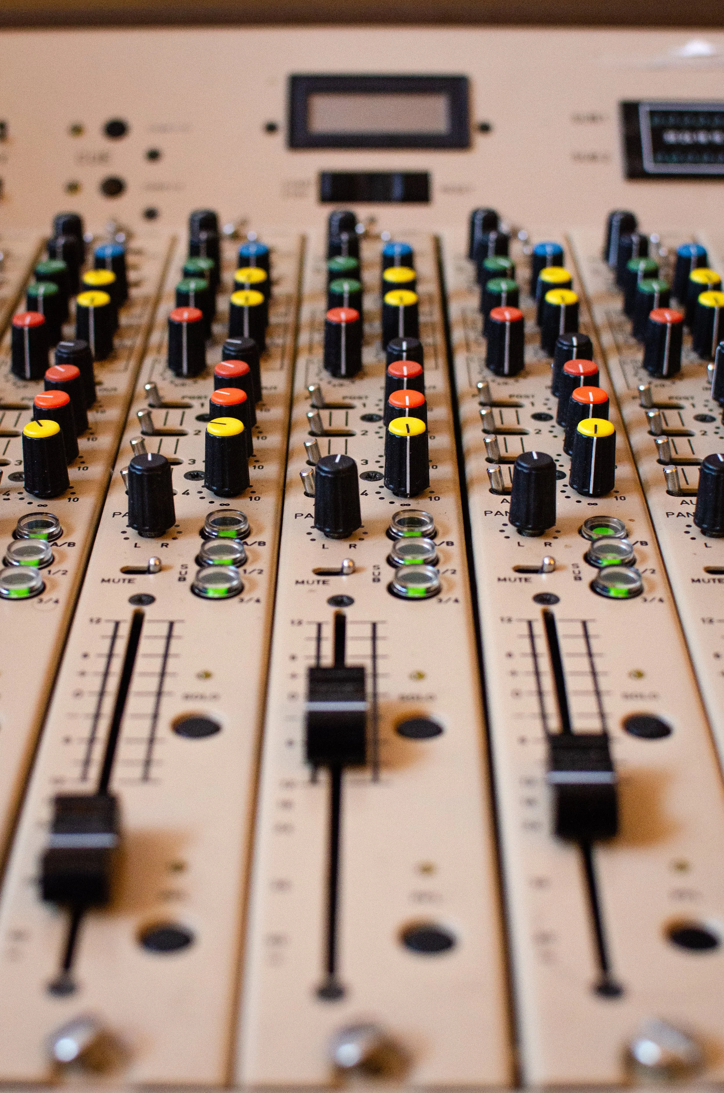 Et lydmiksebord med flere kontrollere, fargede knapper og justeringsspaker.