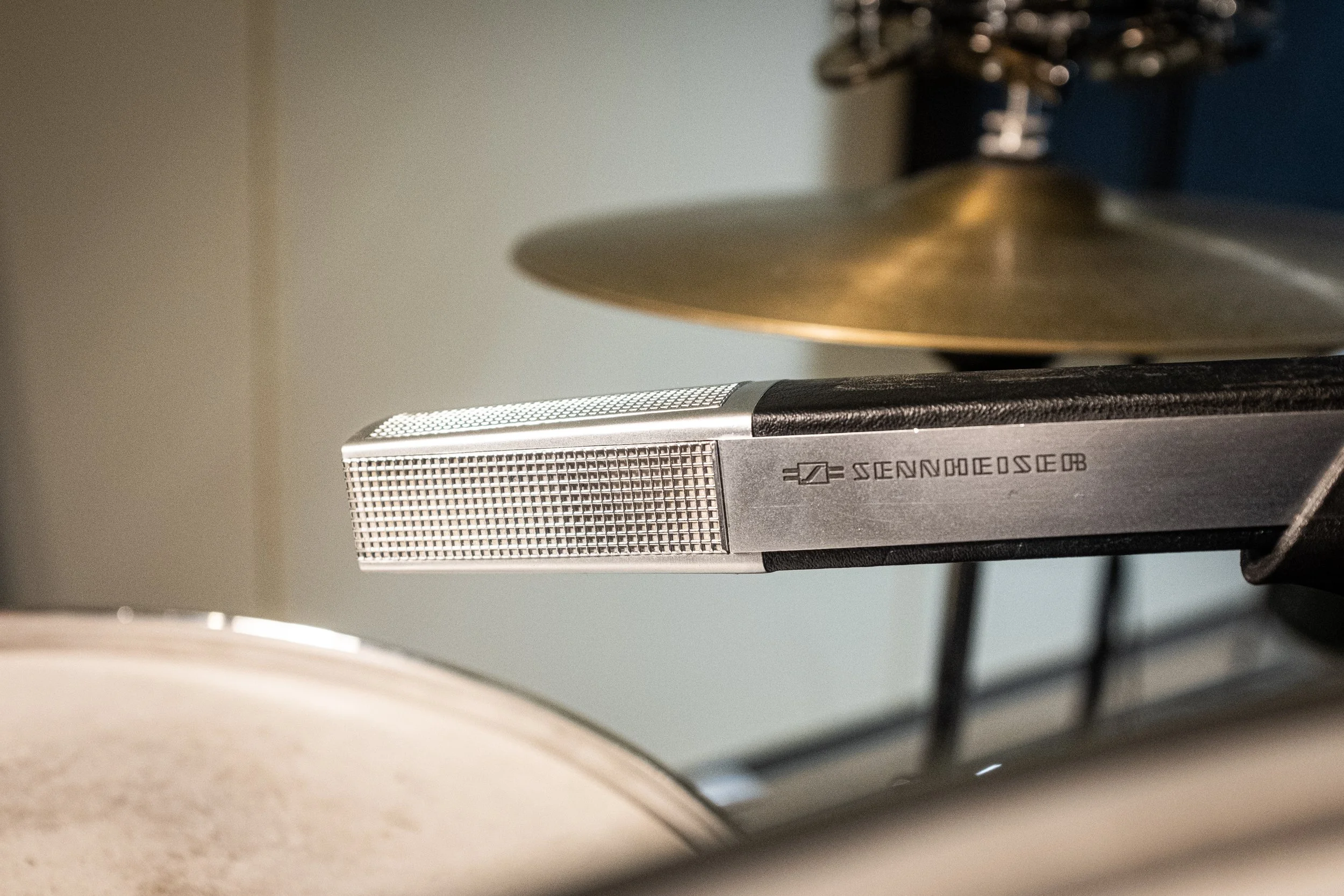 Nærbilde av en metallisk mikrofon plassert på en trommeseksjon i et musikkstudio.