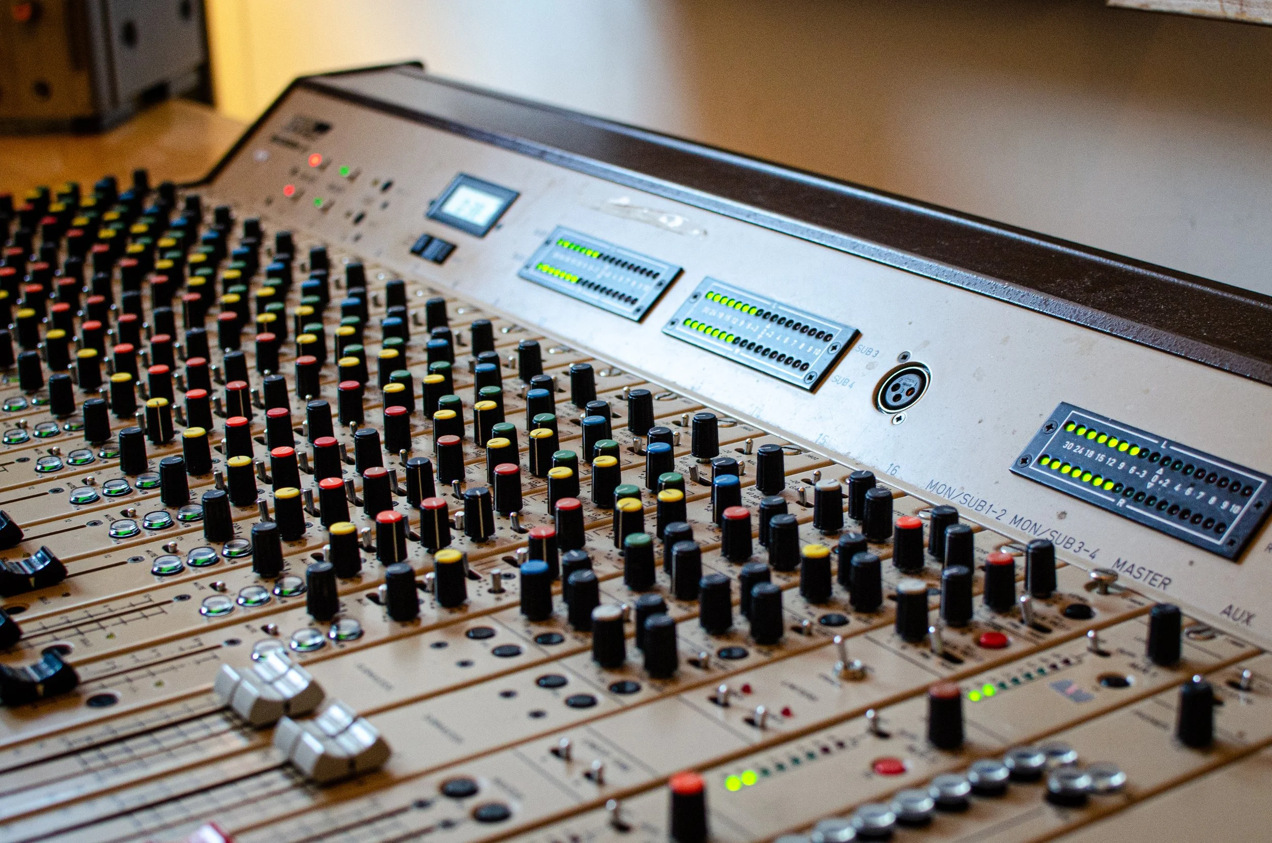 Lydteknisk miksebord med mange justeringsknapper og skjermer, brukt i lydkontrollrom.