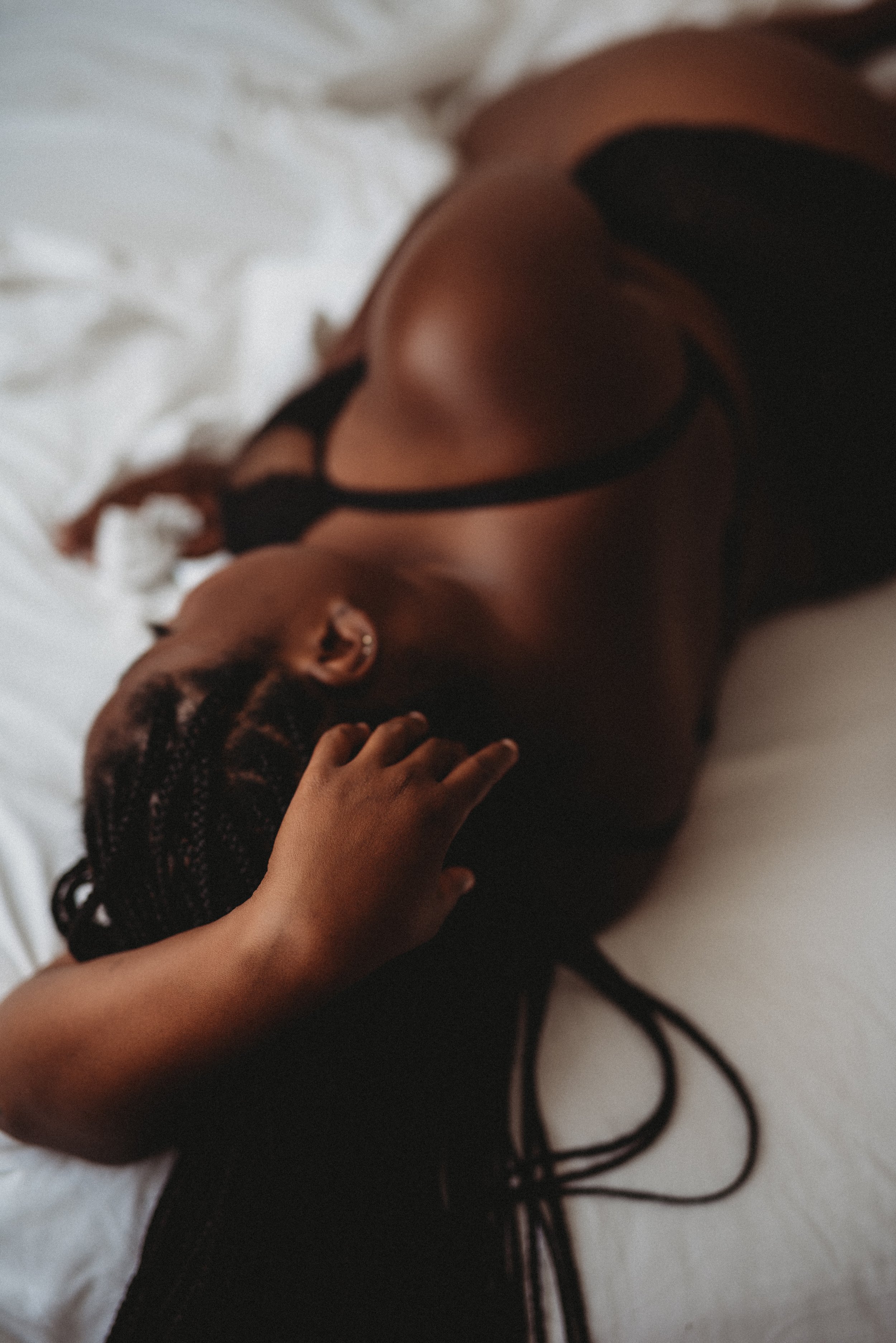 woman lies across bed in boudoir studio in Dover