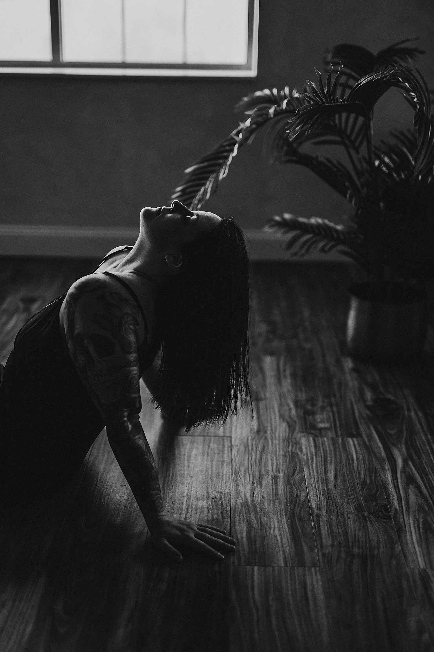  person sits on floor and leans back with face up to ceiling by Hannah Mac Studios 