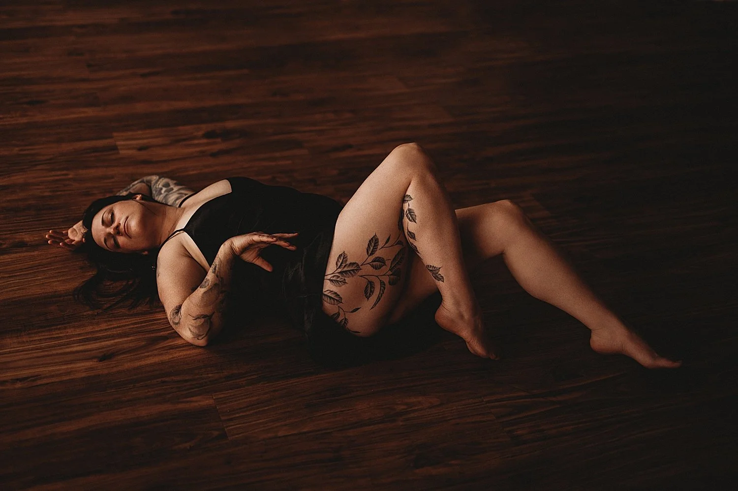  person with tattoos in black lingerie on the floor for empowering session 