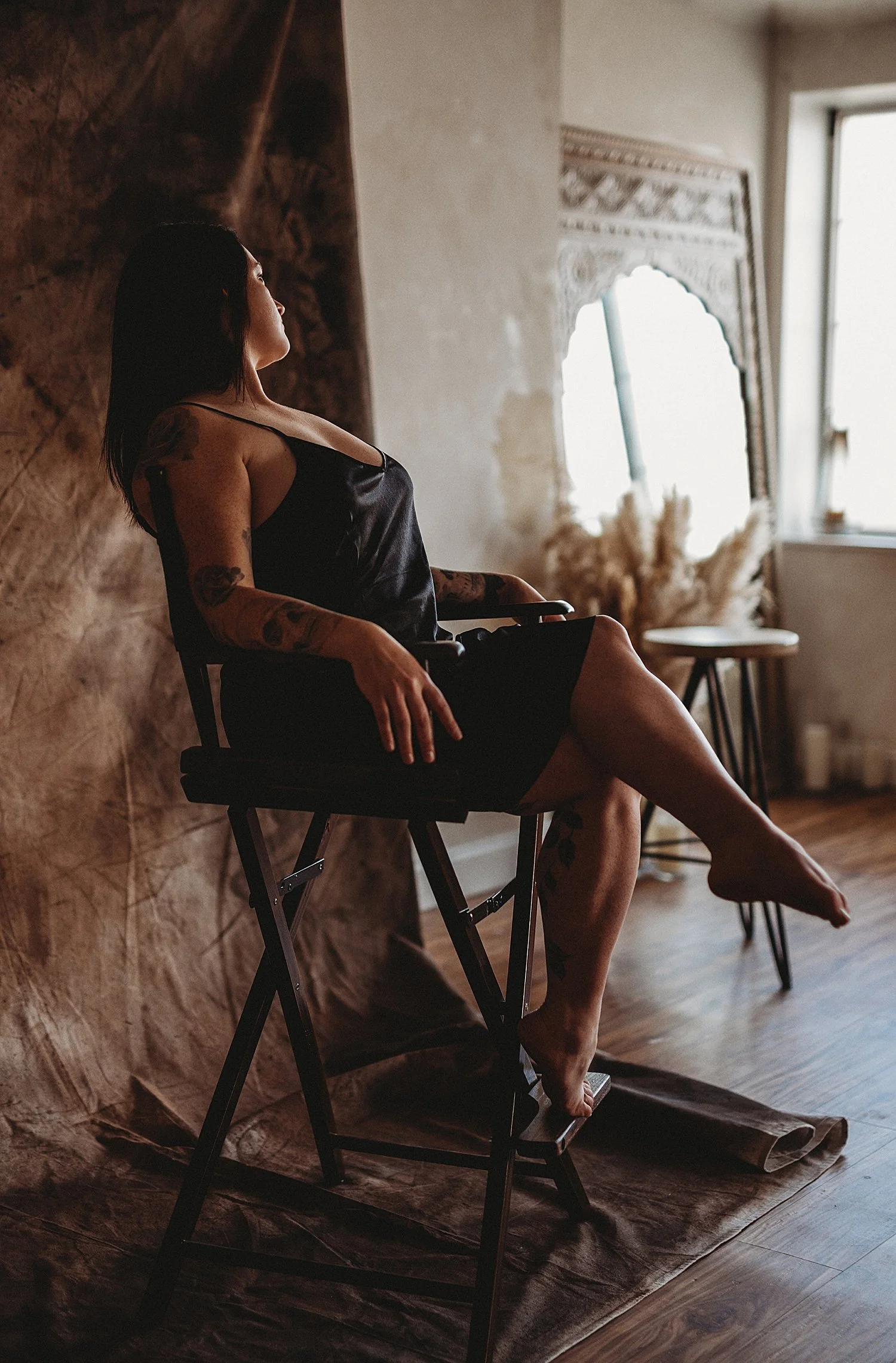  model sits in director style chair in front of backdrop by New Hampshire Boudoir Photographer 