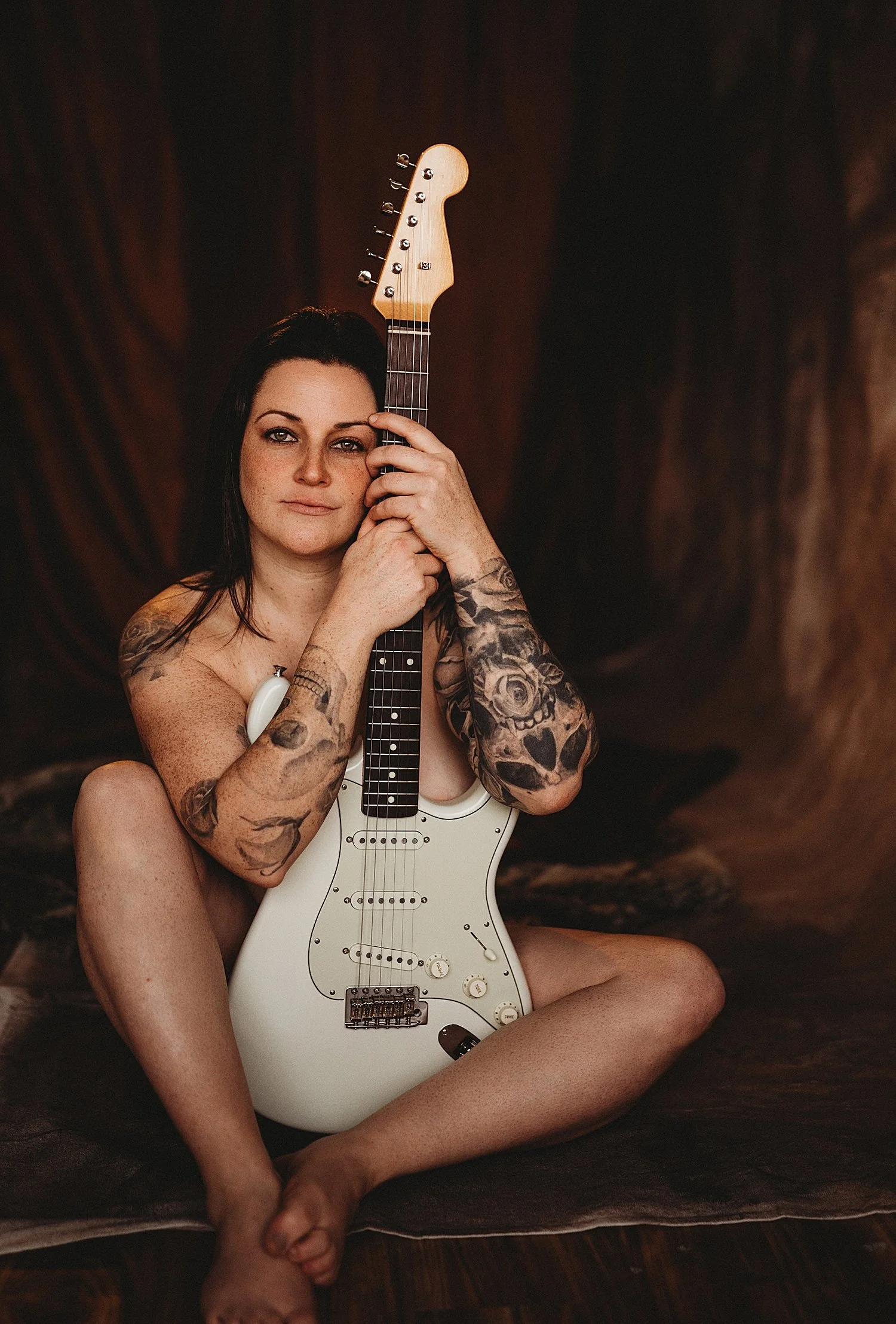  brunette sits on the floor in the nude covering with instrument by New Hampshire Boudoir Photographer 
