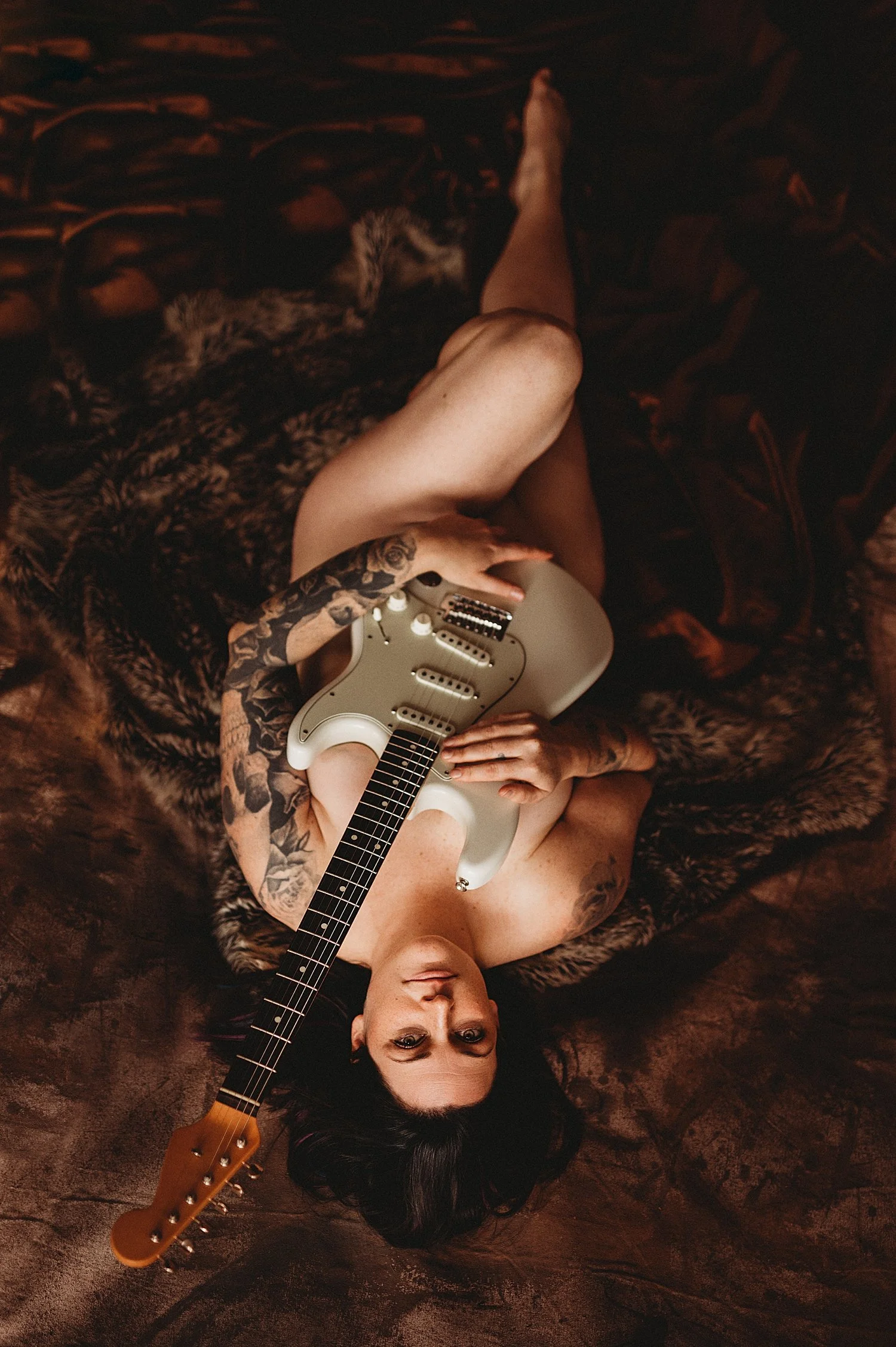  nude woman lies on guitar, covering herself with guitar for empowering session 