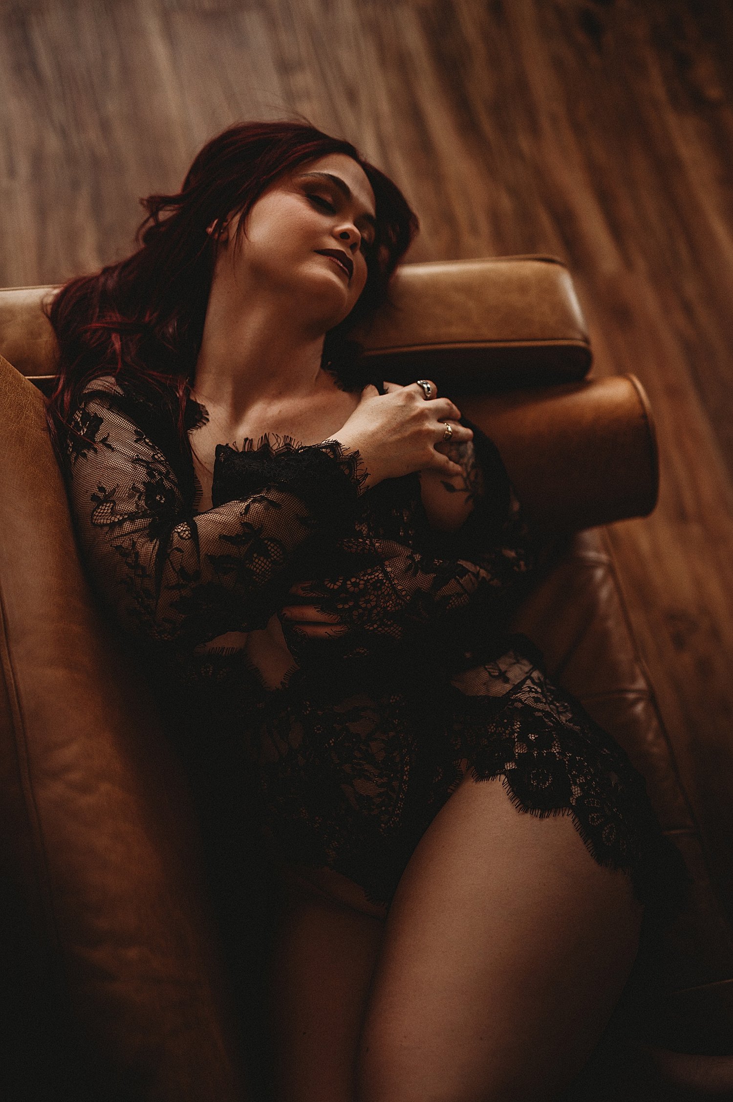  woman on leather couch in lacy outfit by New Hampshire boudoir photographer 