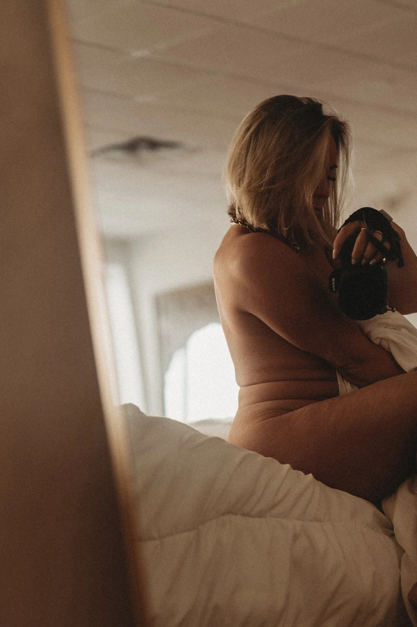 nude woman on bed with sheet by Hannah Mac Studios