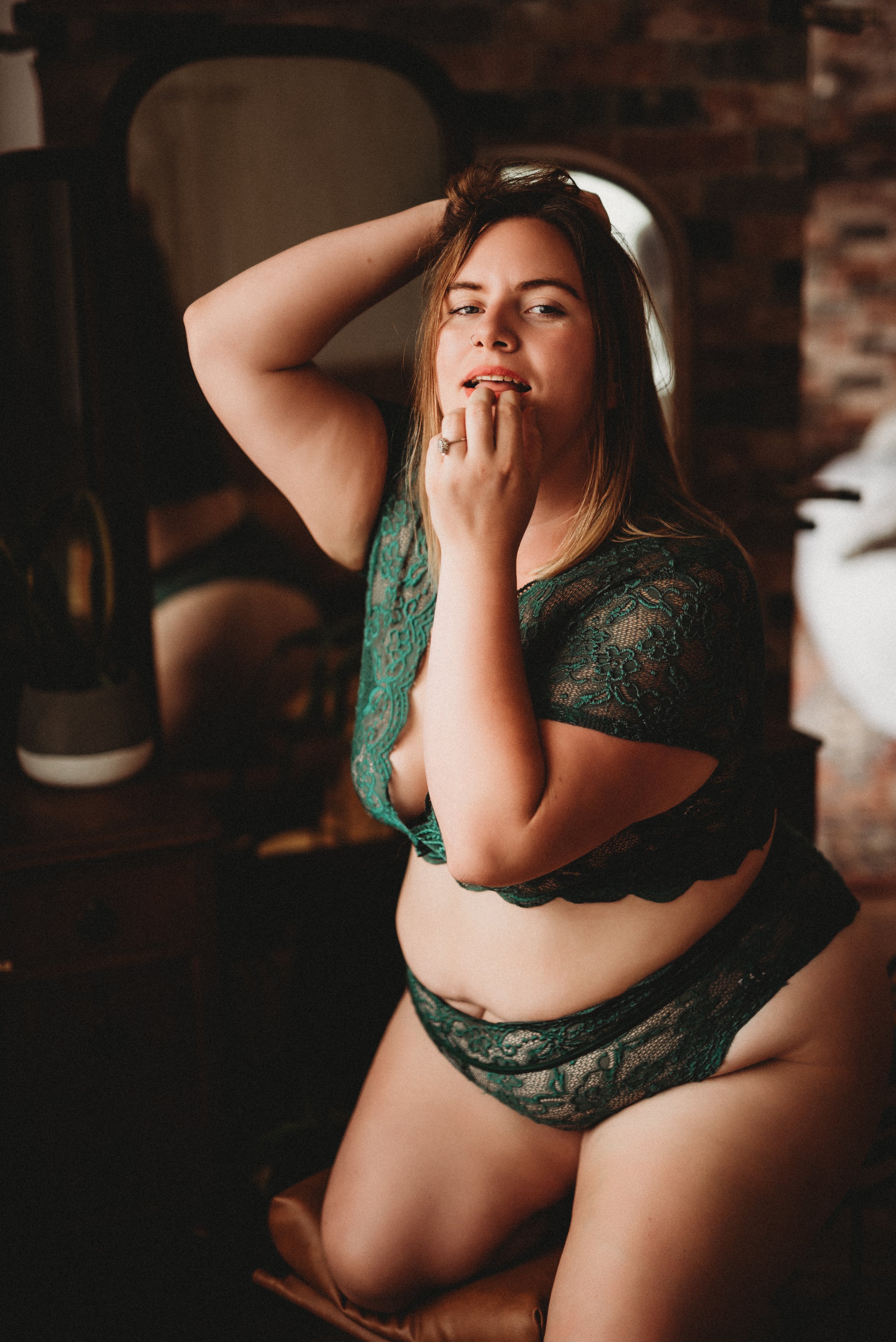 Person in green lace lingerie posing in front of a mirror.