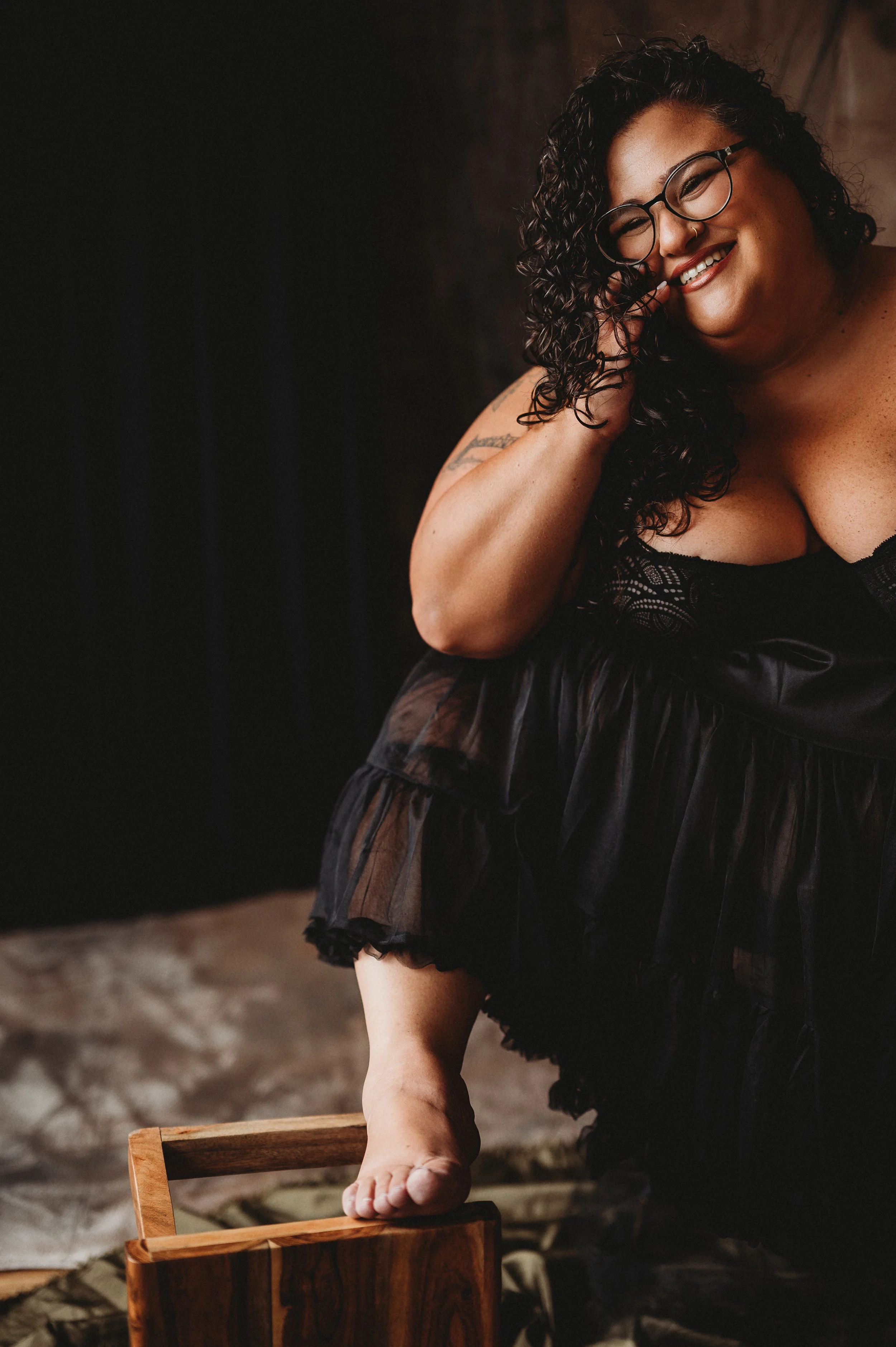 curly haired woman sits on the floor by New Hampshire boudoir photographer