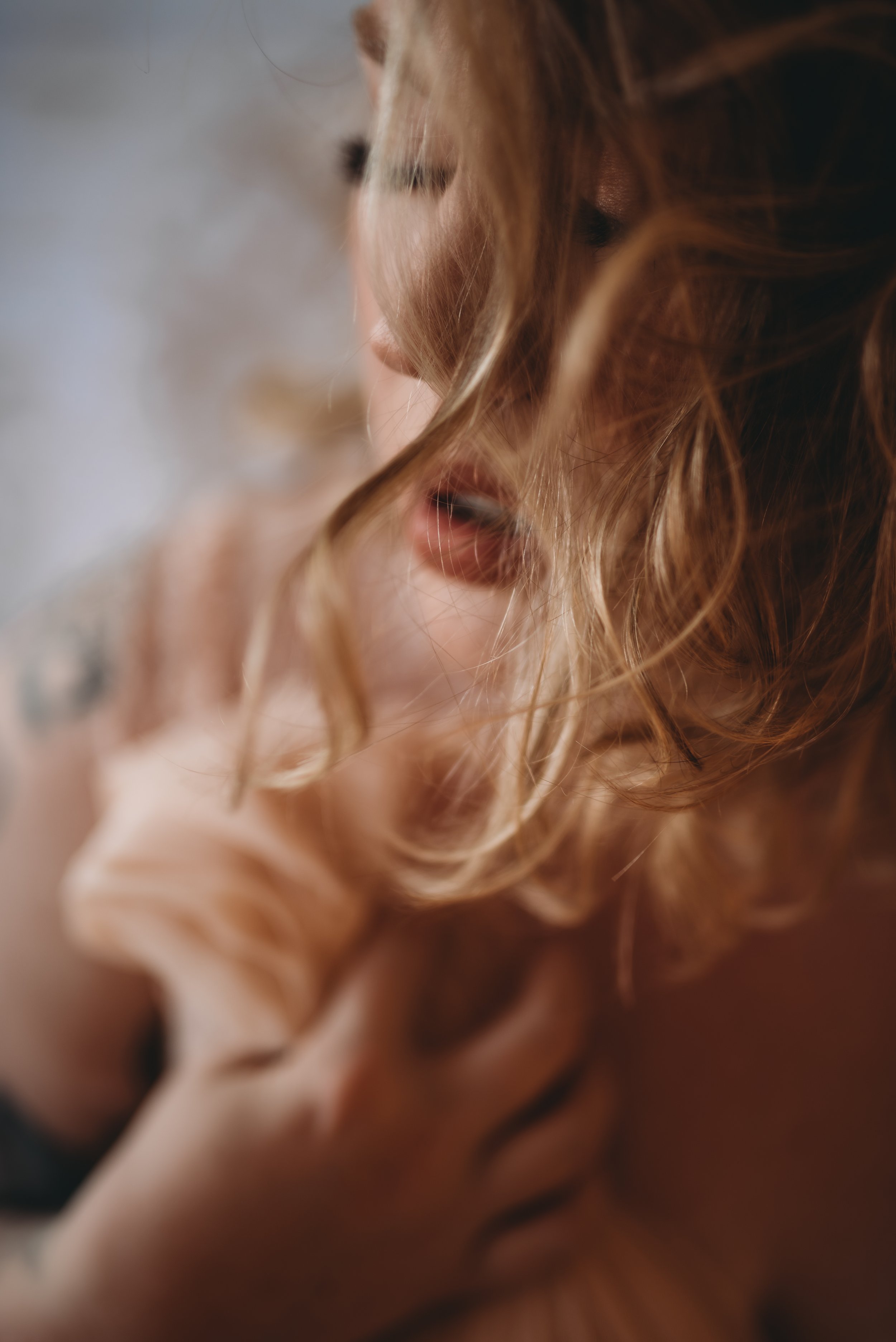 Close-up of a person with curly blonde hair and blurred facial features.
