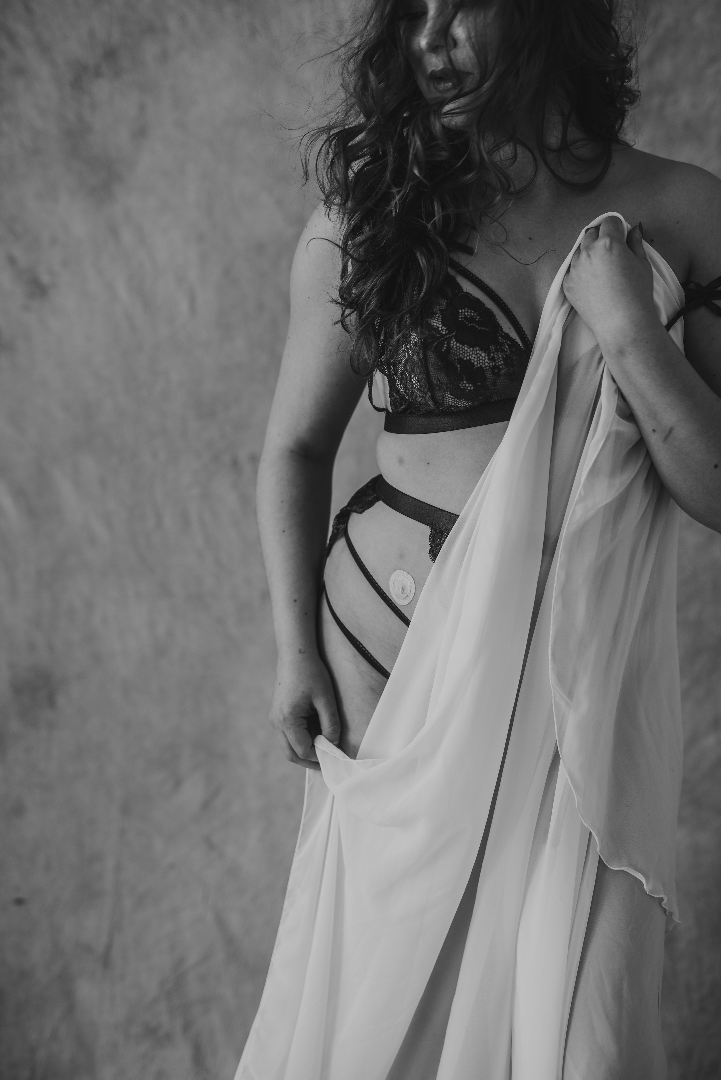 Black and white photo of woman in lingerie holding a draped cloth.