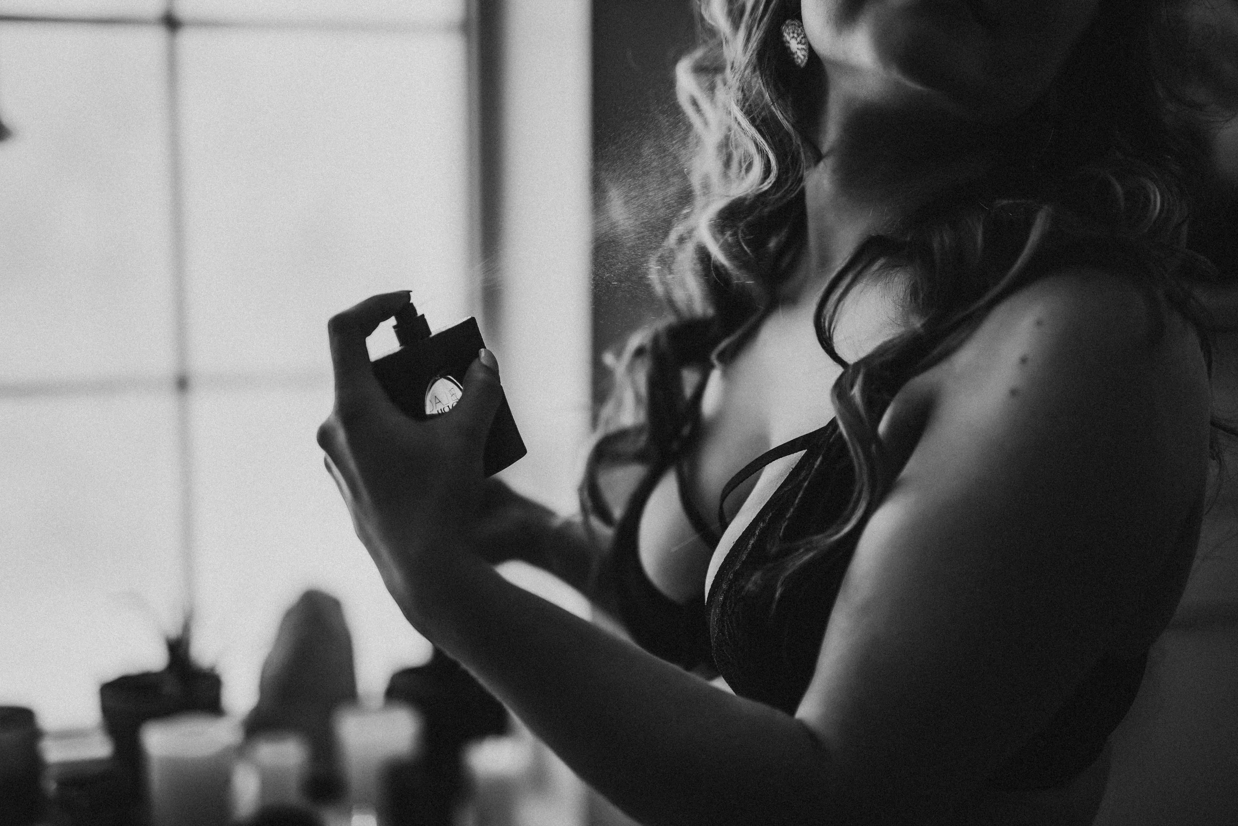 model spritzes herself with perfume during empowering photo session