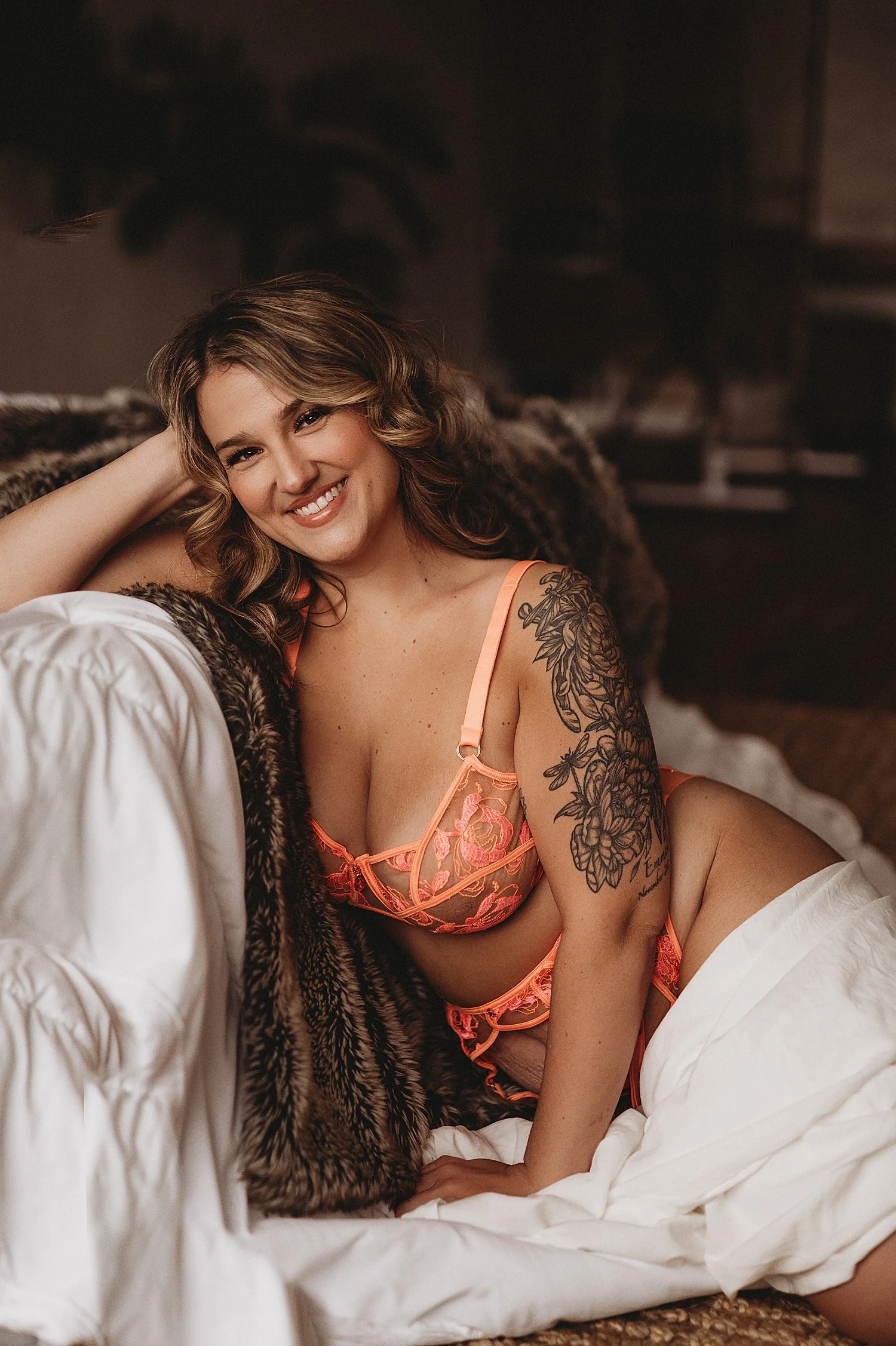 blonde in coral bra leans against bed by New Hampshire boudoir photographer
