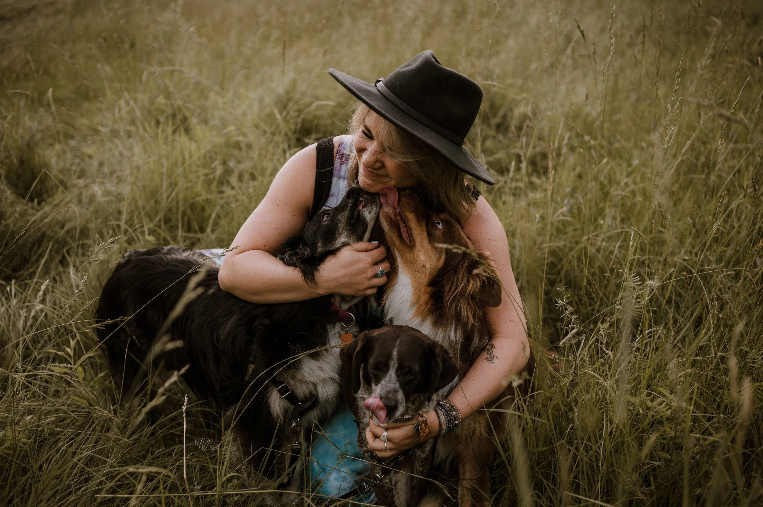 blonde woman snuggles dogs in a field by New Hampshire boudoir photographer