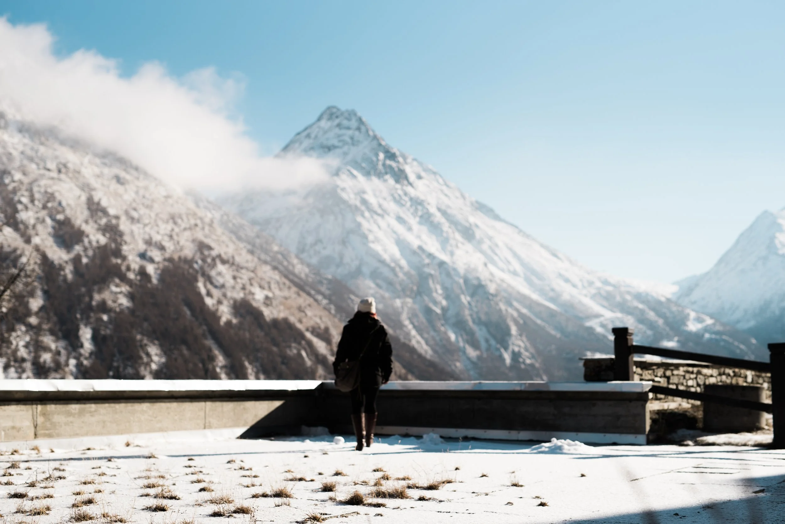 woman stands on lookout over mountain view by Hannah Mac Studios
