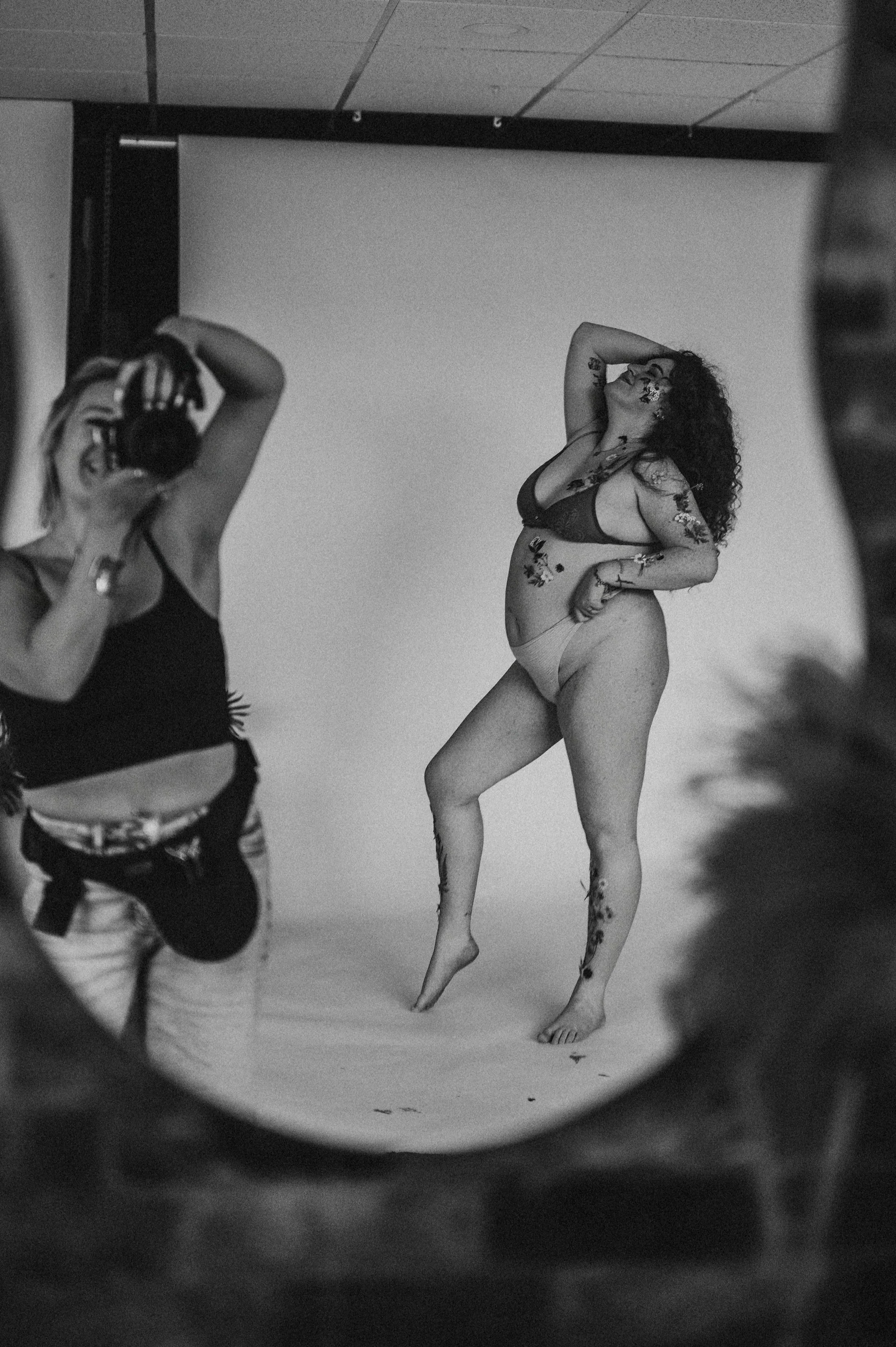 woman with flowers taped on her body stands in front of camera