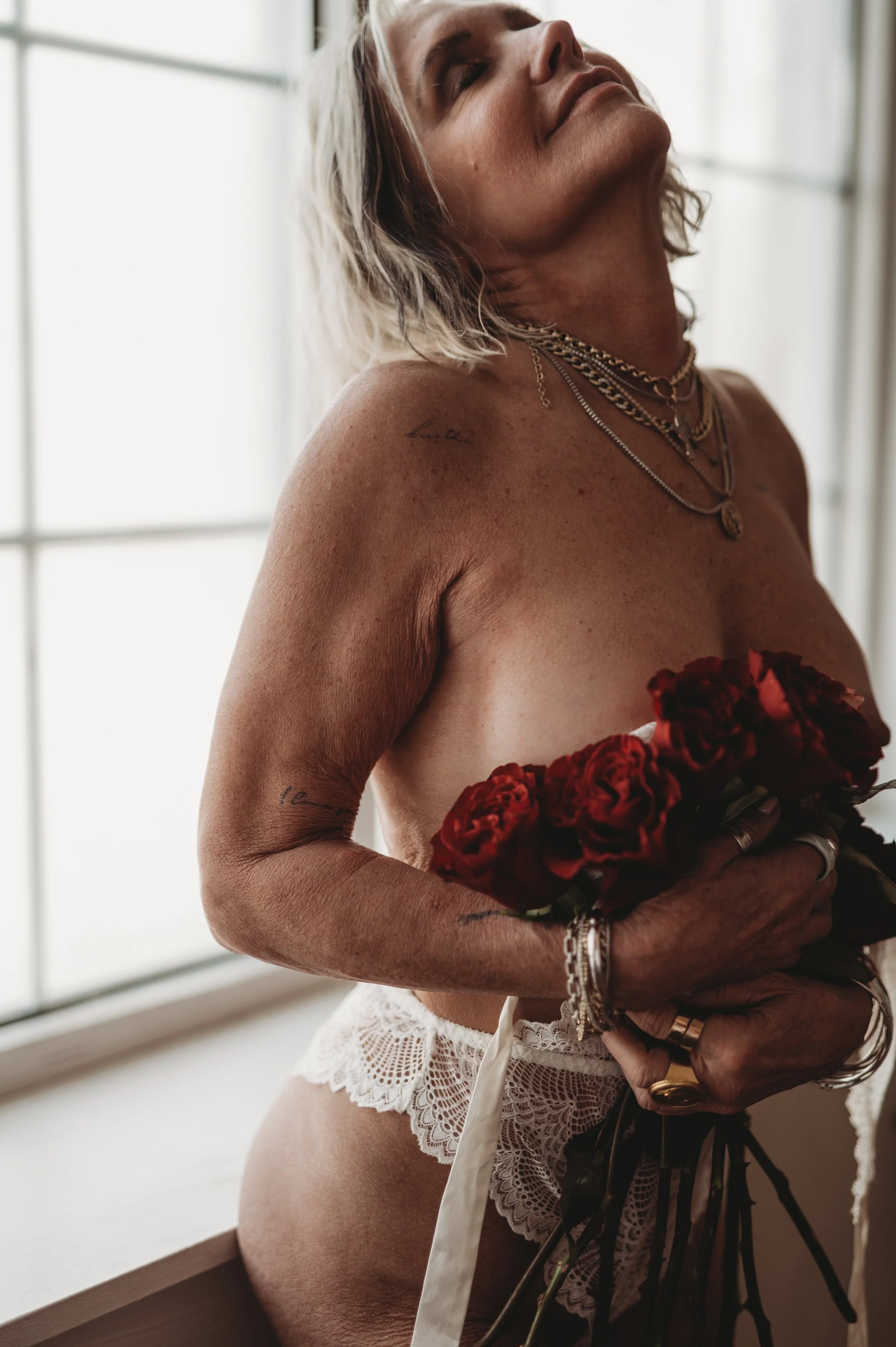 mature nude woman holds roses over herself in Hannah Mac Studios