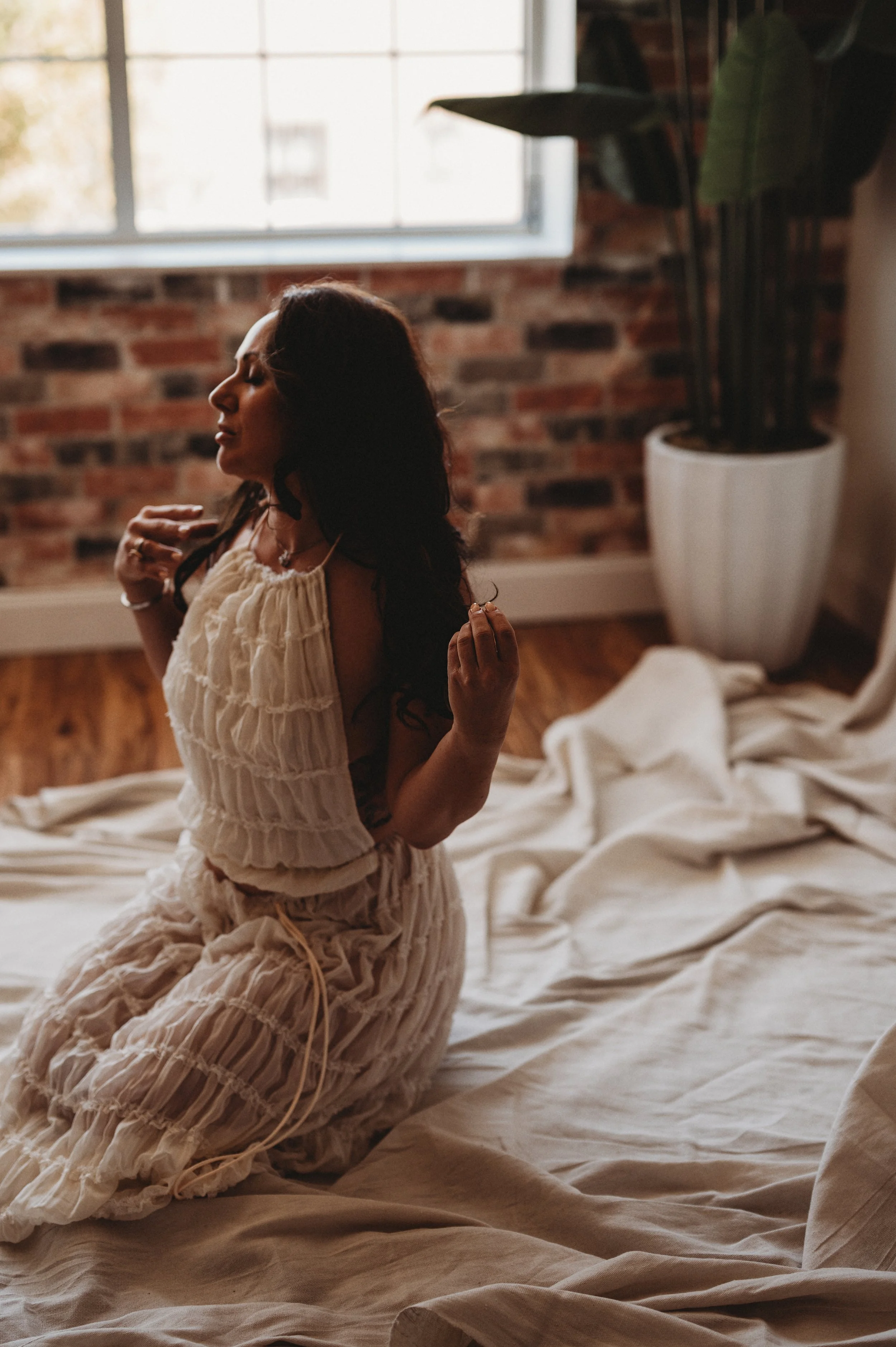 model sits on floor wearing white dress by Hannah Mac Studios