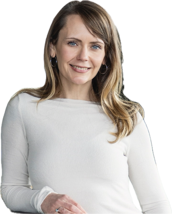 A woman with long blonde hair, wearing a white long sleeve top, smiling and looking at the camera, with earrings.
