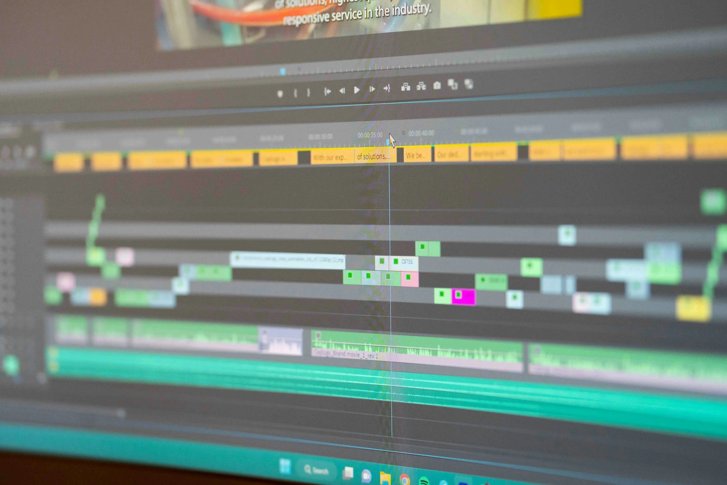 Screenshot of a video editing timeline with multiple tracks of video clips, audio, and color-coded markers on a computer monitor.