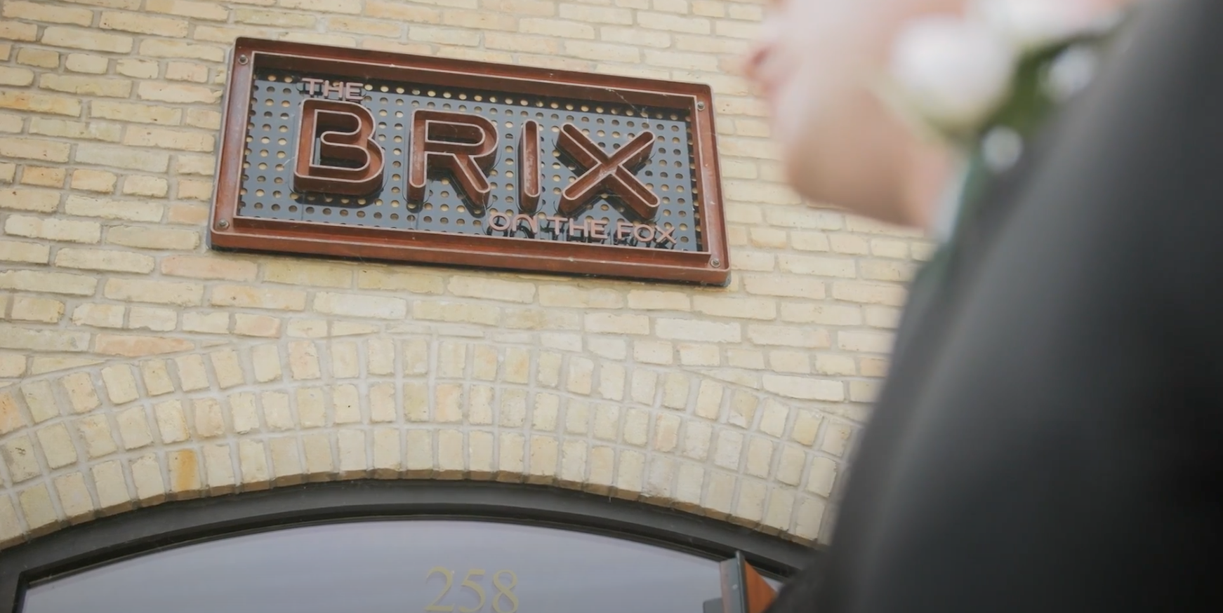 Sign reading 'The Brix on the Fox' mounted on a brick building front with the address number 258 below an arched window.