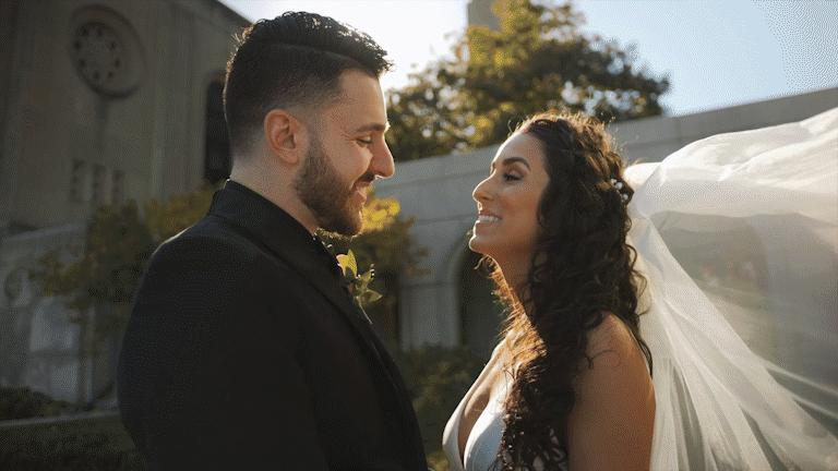 A bride and groom smiling at each other outdoors during sunset.