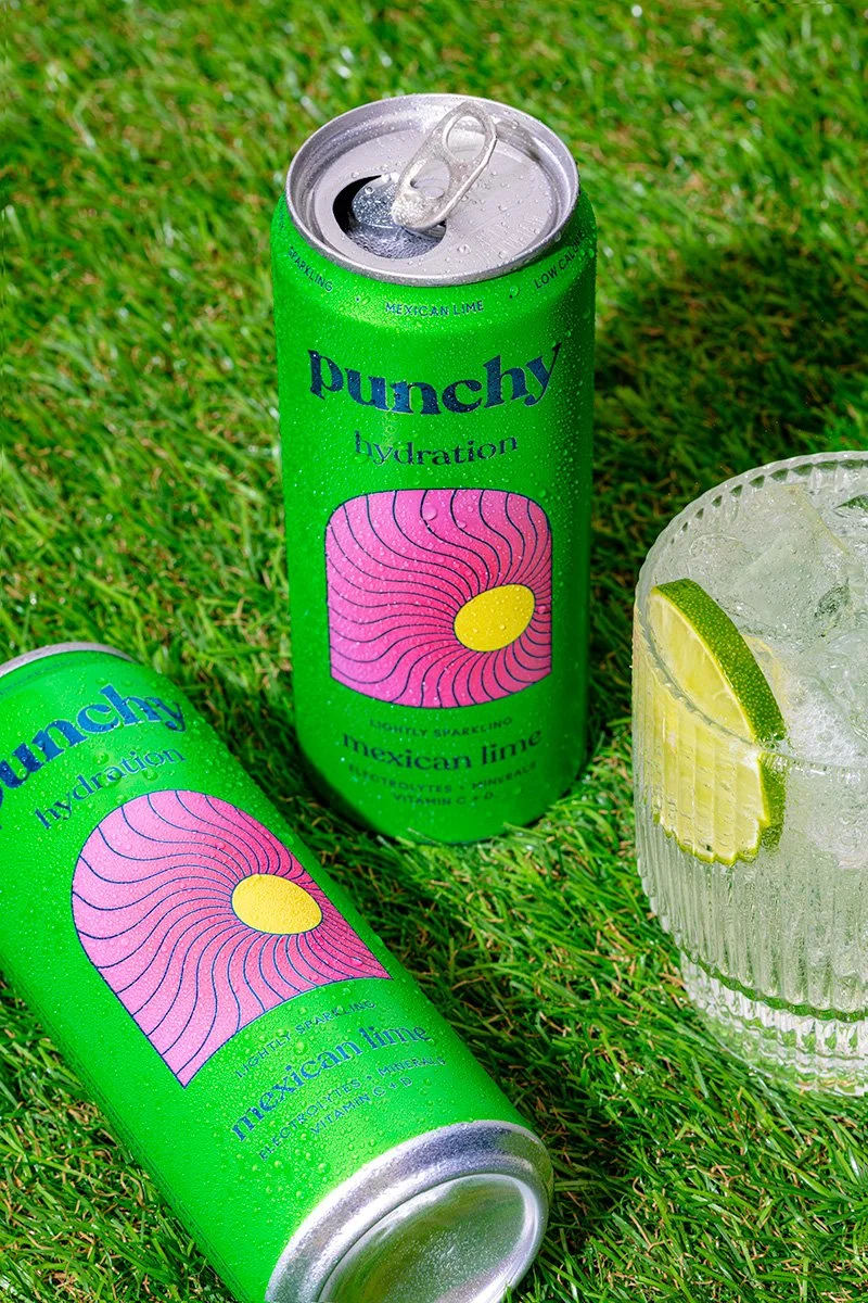 cold cans of punchy drink photographed outside on grass during a hot summer day