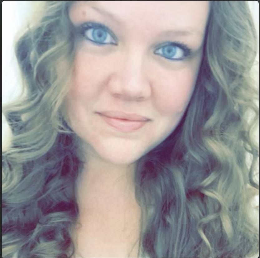 Close-up of a woman with blue eyes and long, curly brown hair.