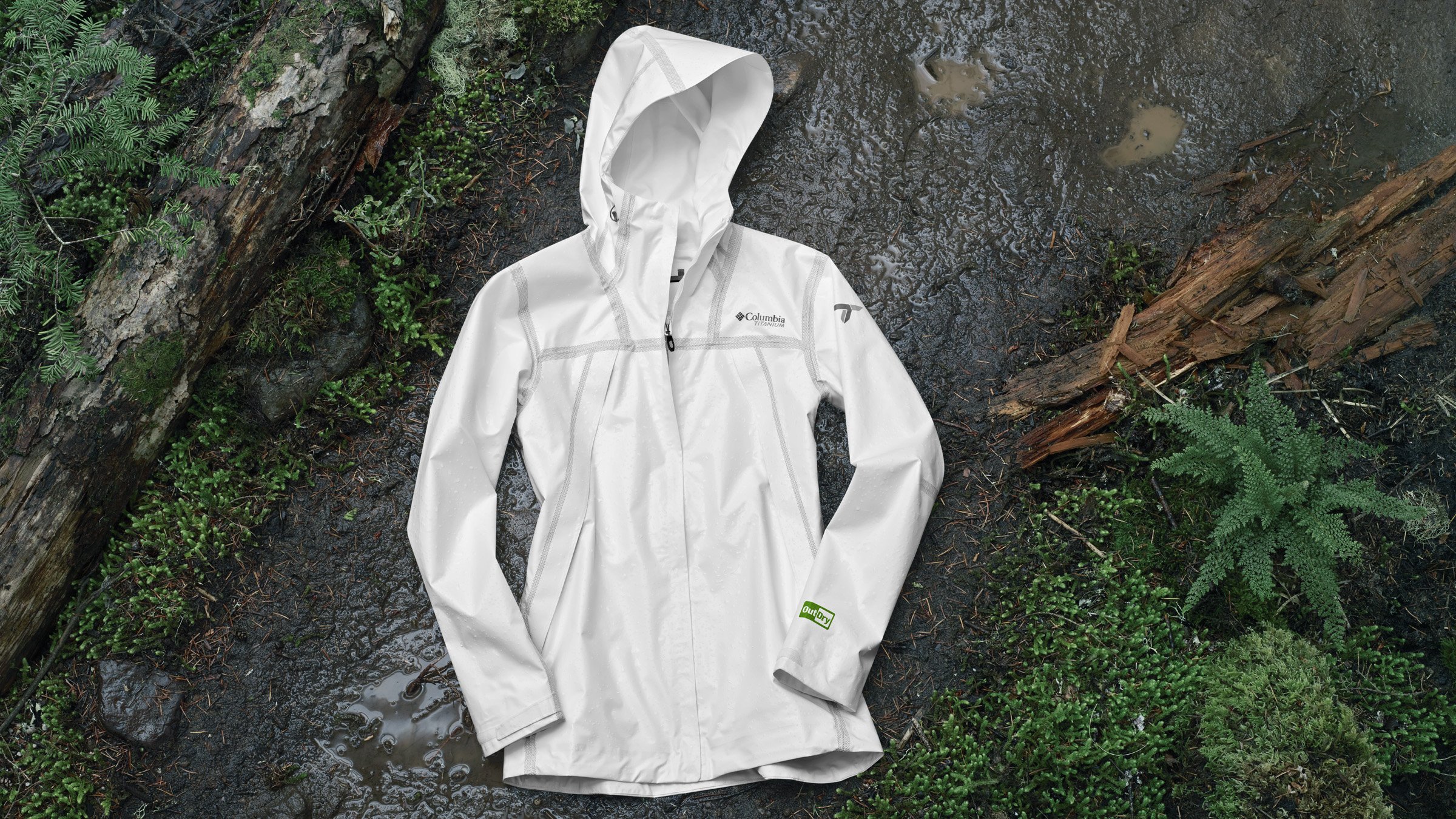 White Columbia Sportswear rain jacket displayed on a wet forest trail.