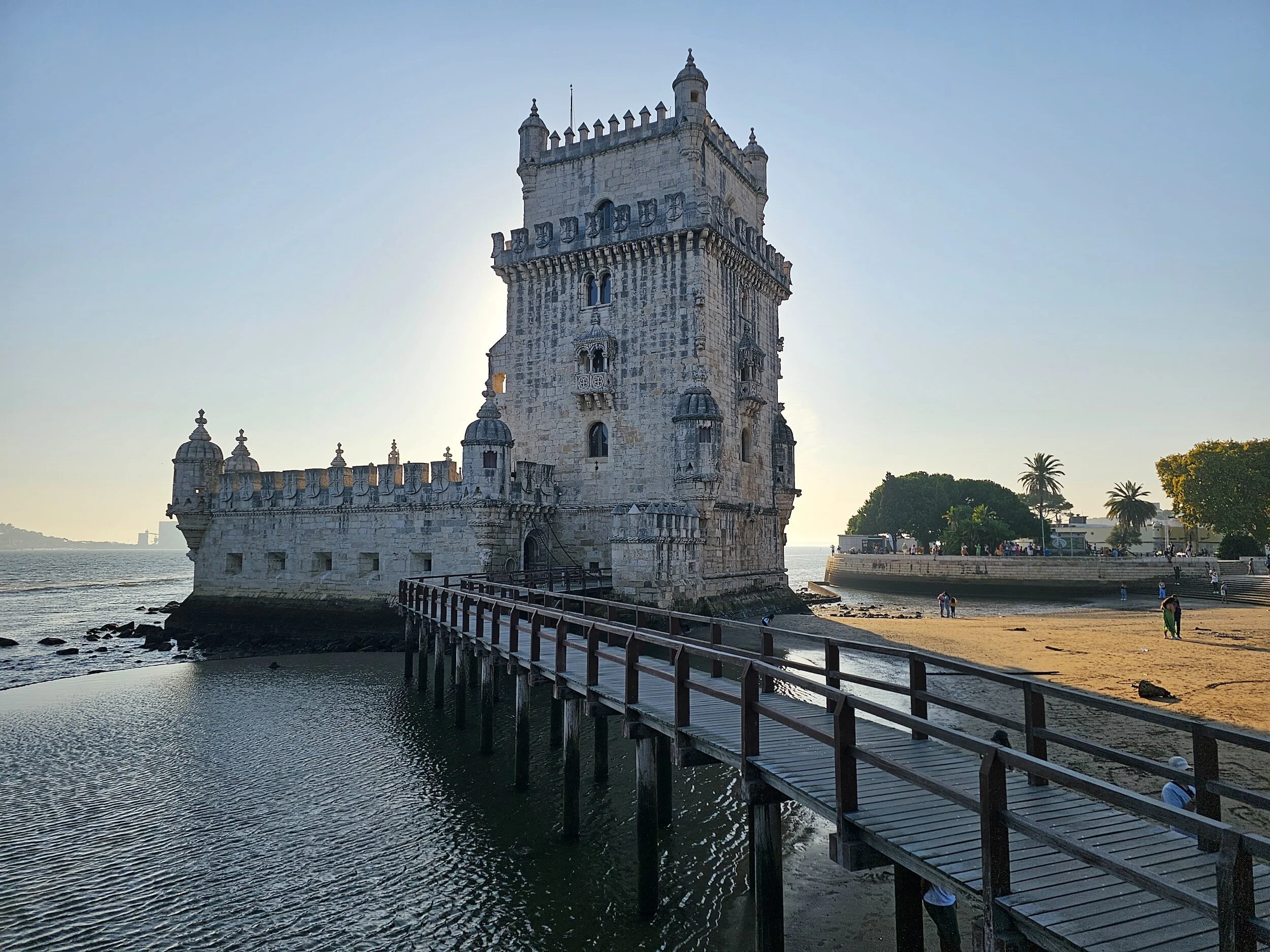Belem Tower in Lisbon, Portugal, at sunset with a boardwalk and waterfront scenery.