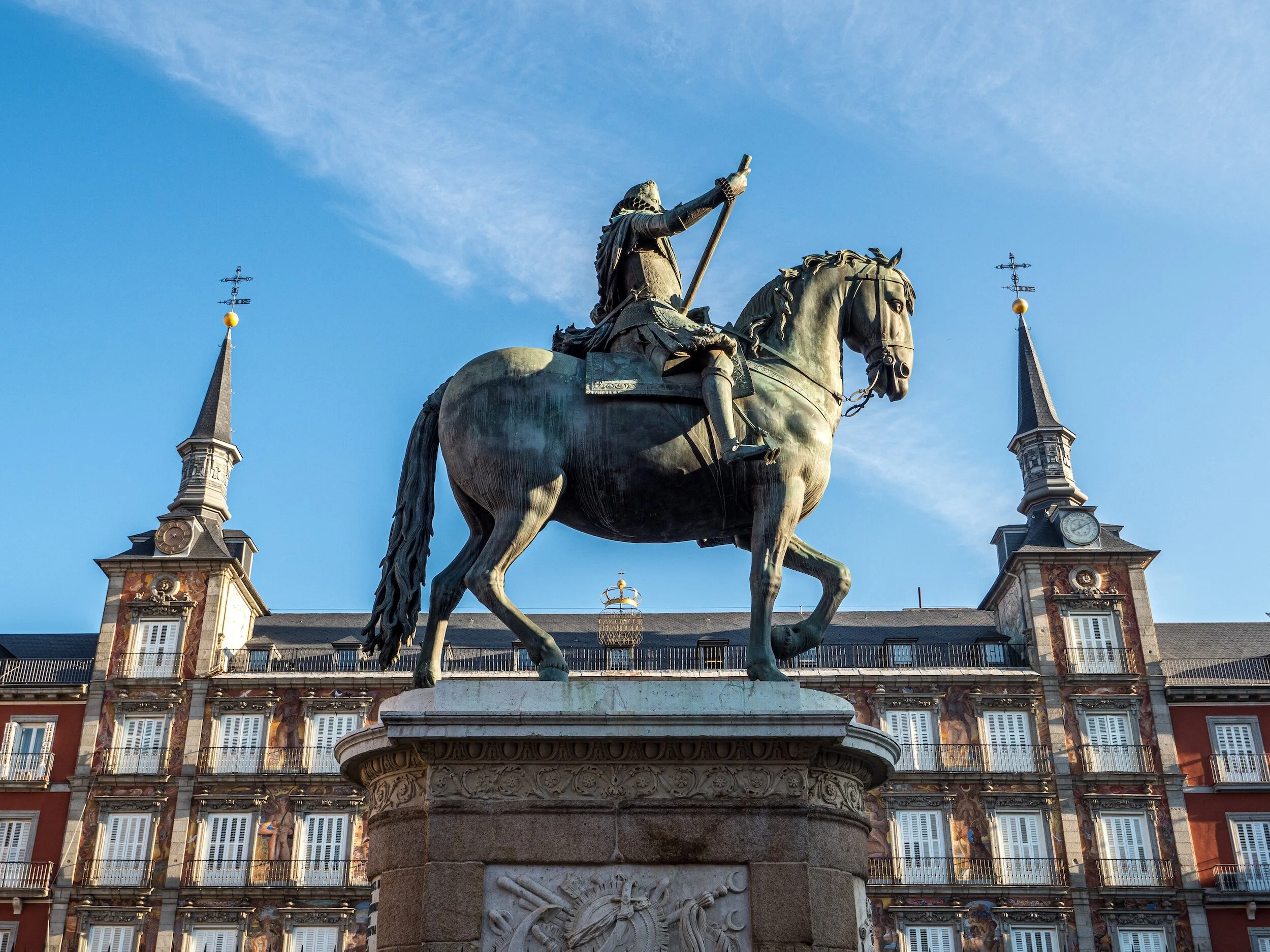 Statue of a man on a horse in Plaza Mayor, Madrid with historic buildings in the background.